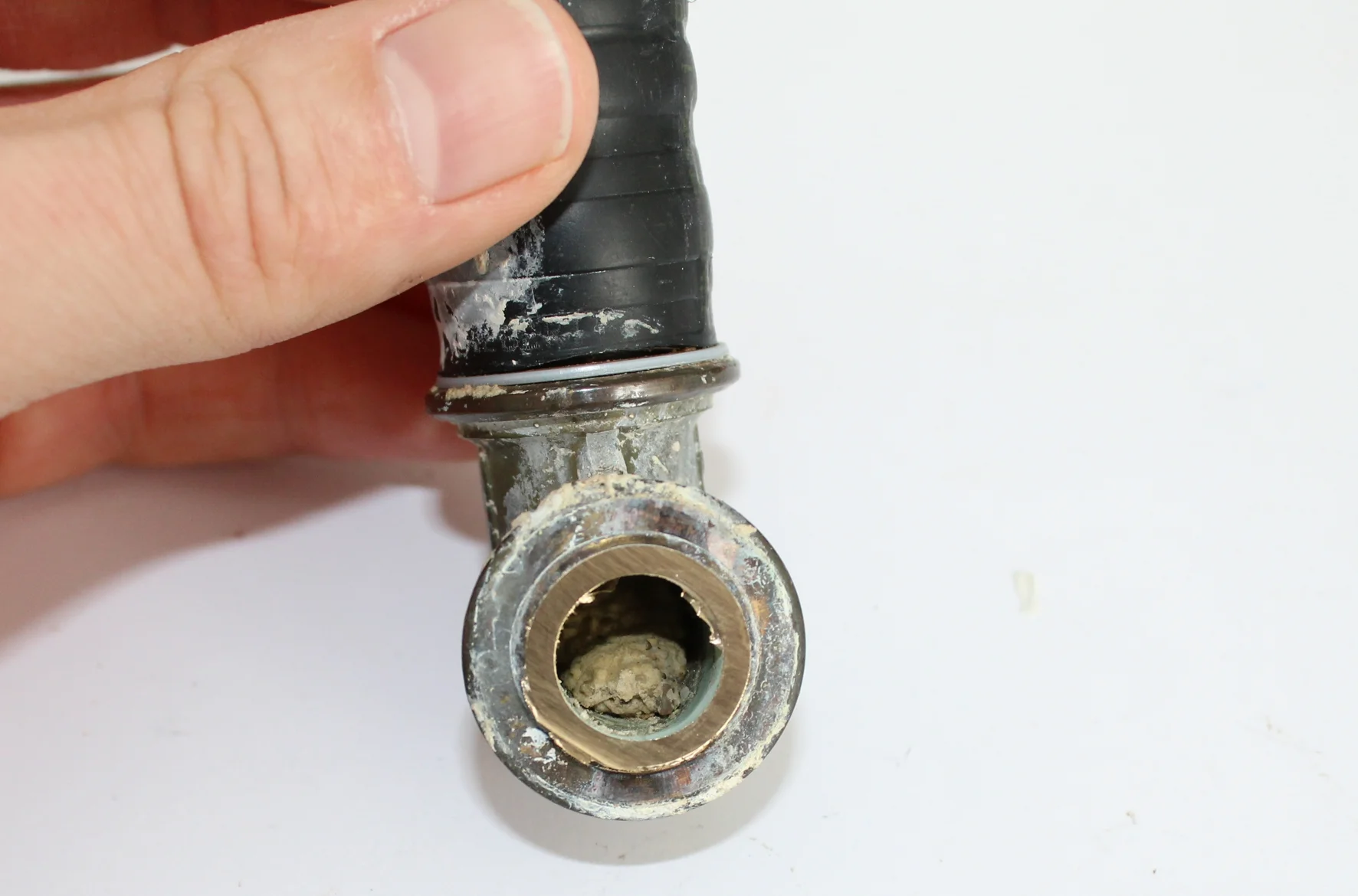   Für die weitere Untersuchung wurden zunächst die Verbundrohre vom Fitting abgetrennt. Ansicht der gekürzten Tülle am Winkel. Der Strömungsquerschnitt ist durch Mörtel, Fliesenkleber, o.ä. stark verengt.  