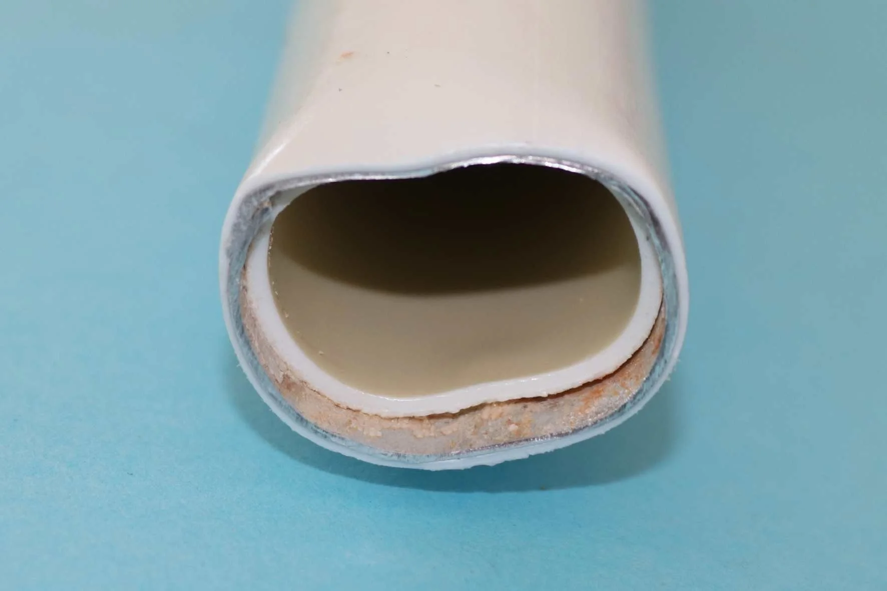  Für weitere Untersuchungen wurde das Rohr im Bereich einer Blase durchtrennt und die Schnittfläche feingeschliffen. Der Haftvermittler zwischen Inliner und Aluminiumrohr ist bräunlich verfärbt. Unter dem Stereomikroskop ist ersichtlich, dass im Bere