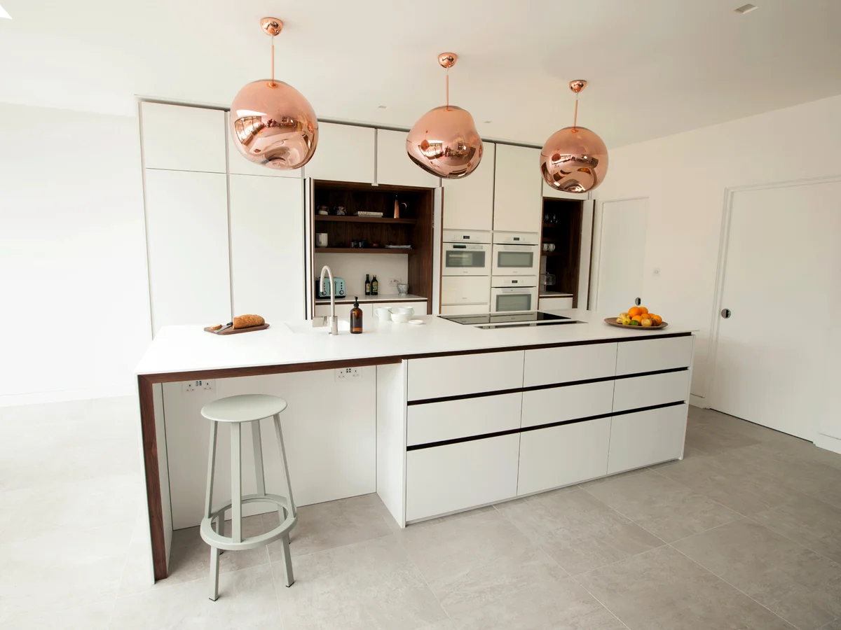 High specification bespoke kitchen by standforth with pocket doors to wall cabinets opened revealing walnut cabinets
