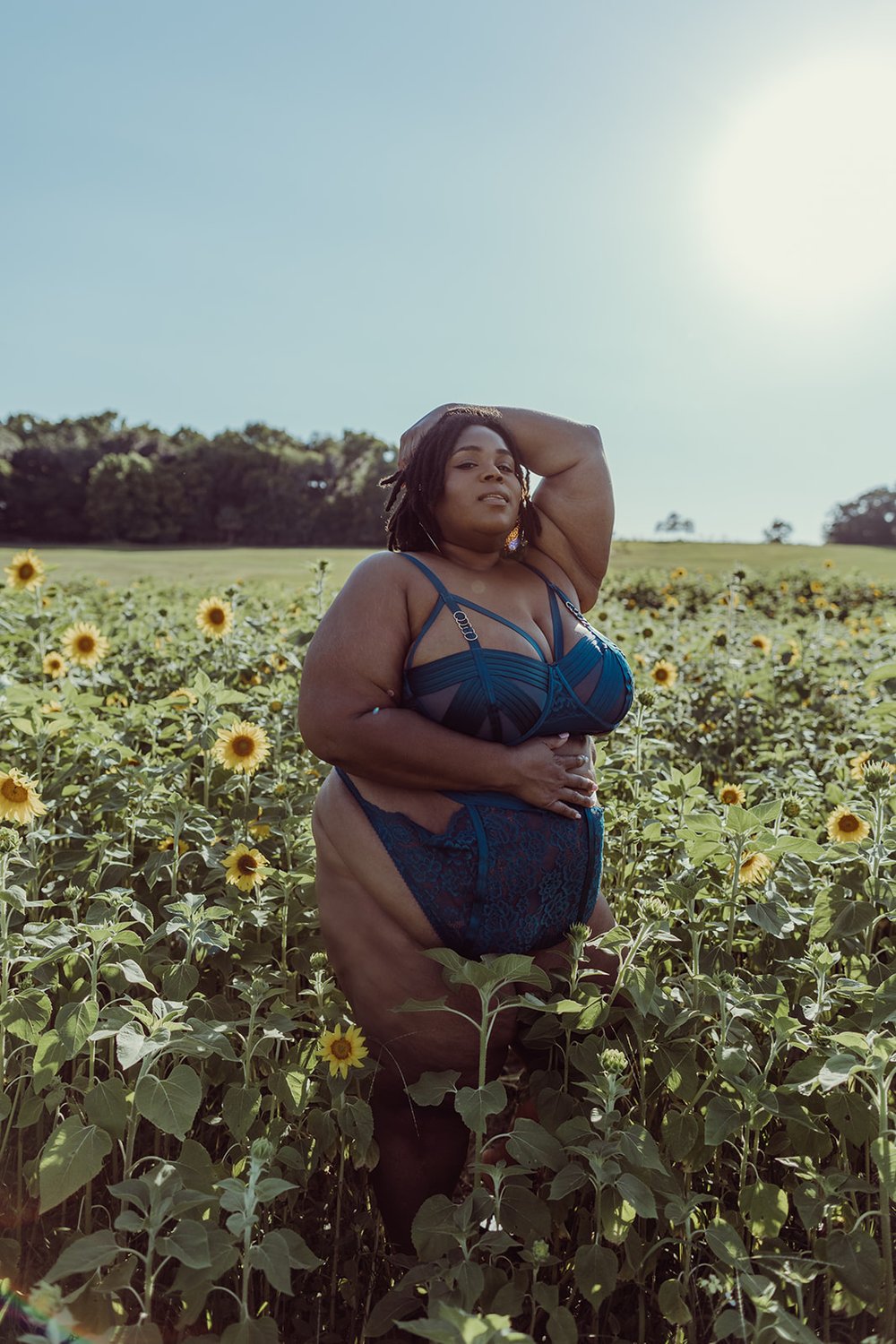  woman standing in a sunflower field gives the camera a sultry gaze during her outdoor boudoir photoshoot in Florida 