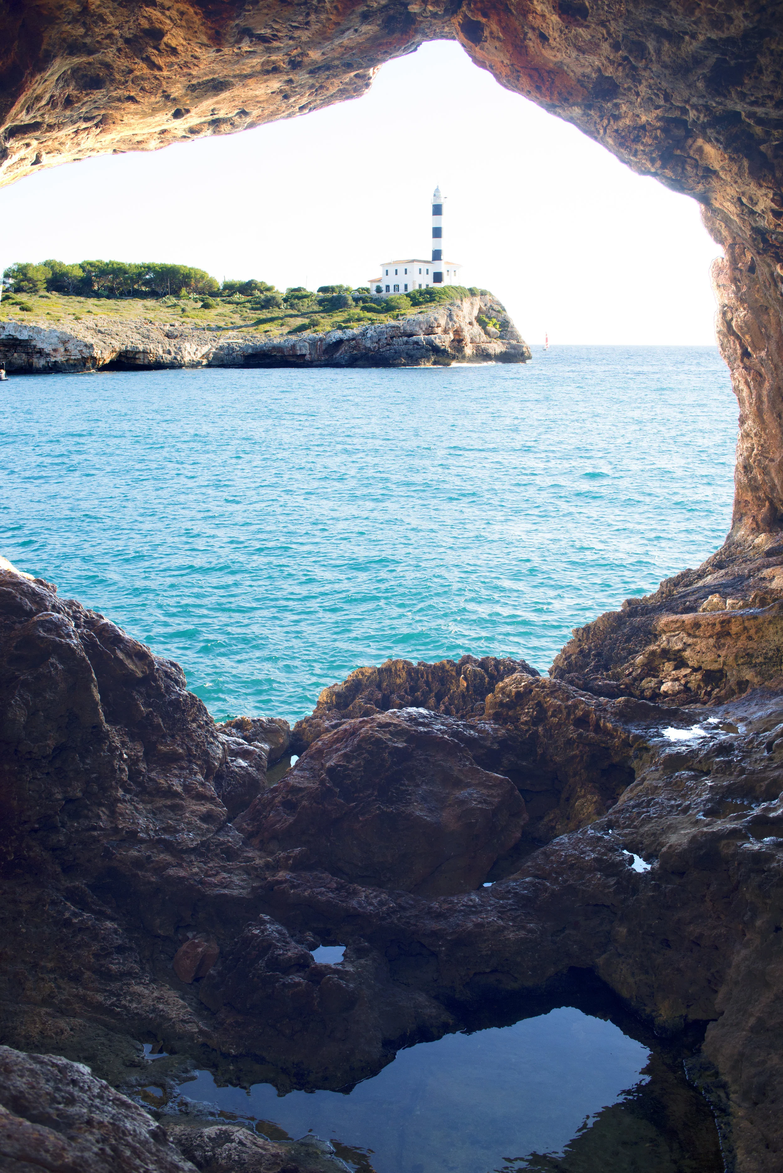 Lighthouse at Ponta de Ses Crest. Photographed from Natural Arch at Portocolom.