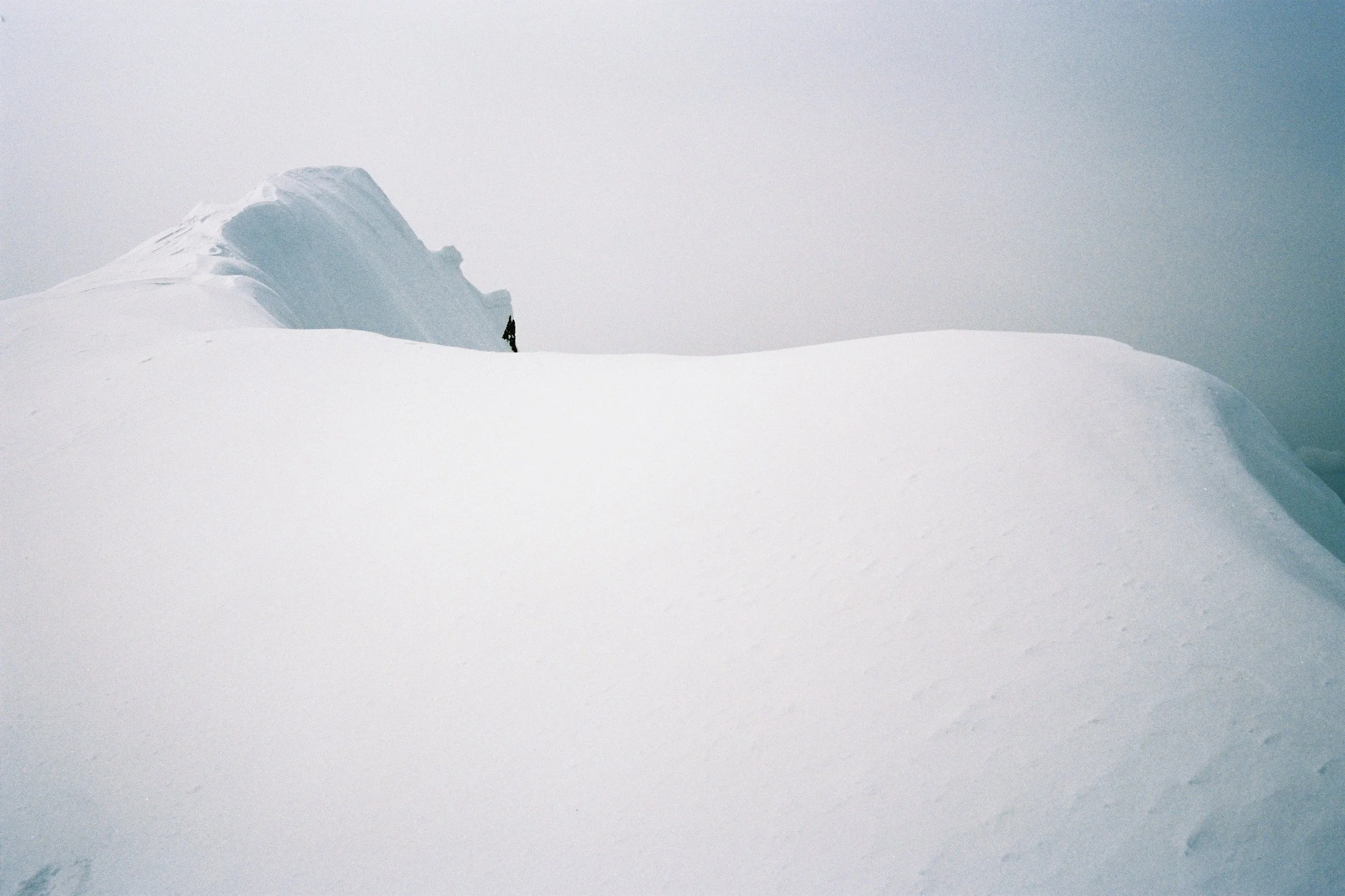 Un paysage de neige avec une petite personne au loin près d'une formation de glace ou d'iceberg