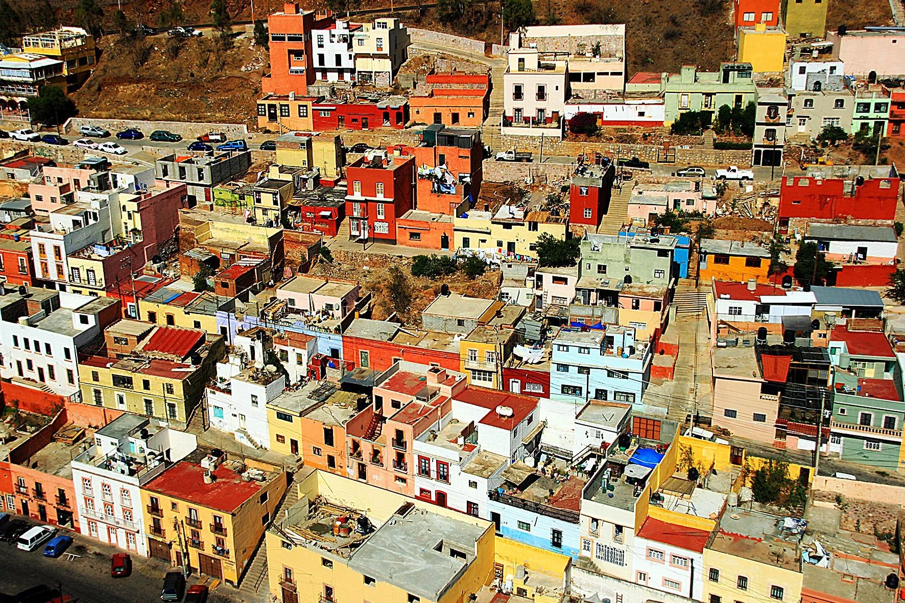Vue aérienne d'un quartier de maisons colorées empilées sur une colline, dans une ville.