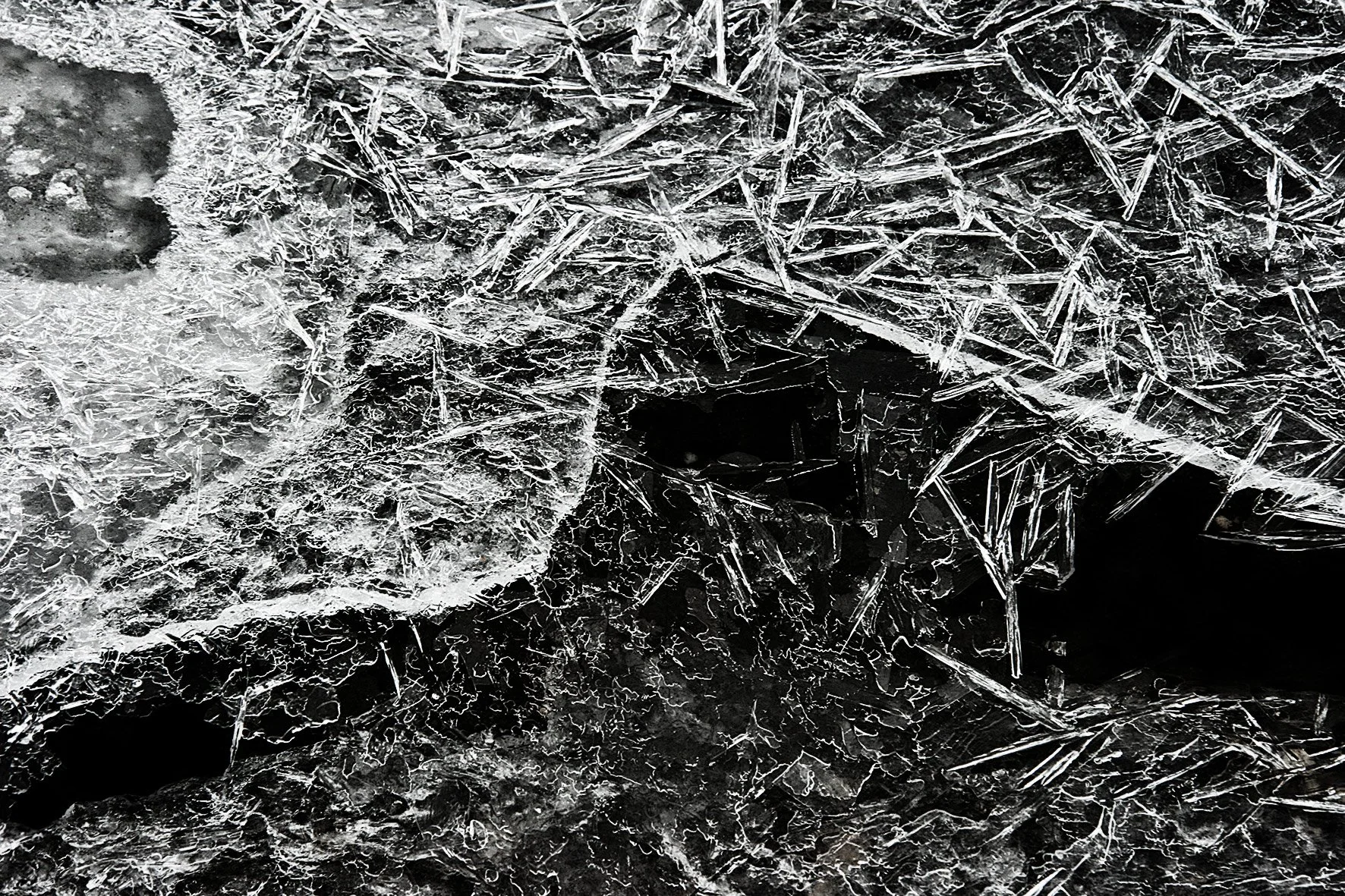 Gros plan d'une surface de glace avec des cristaux et des fissures, montrant des structures de glace complexes et fines.