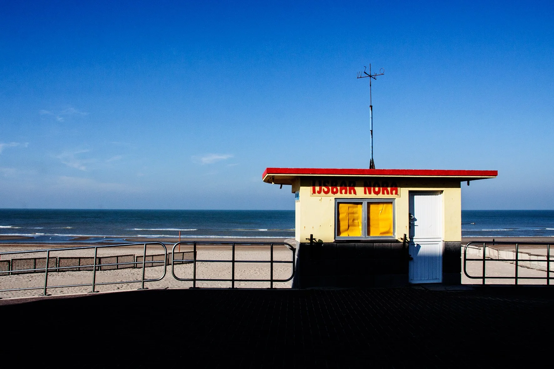 Petite cabane de surveillance de plage située sur le front de mer avec la mer et un ciel bleu en arrière-plan.