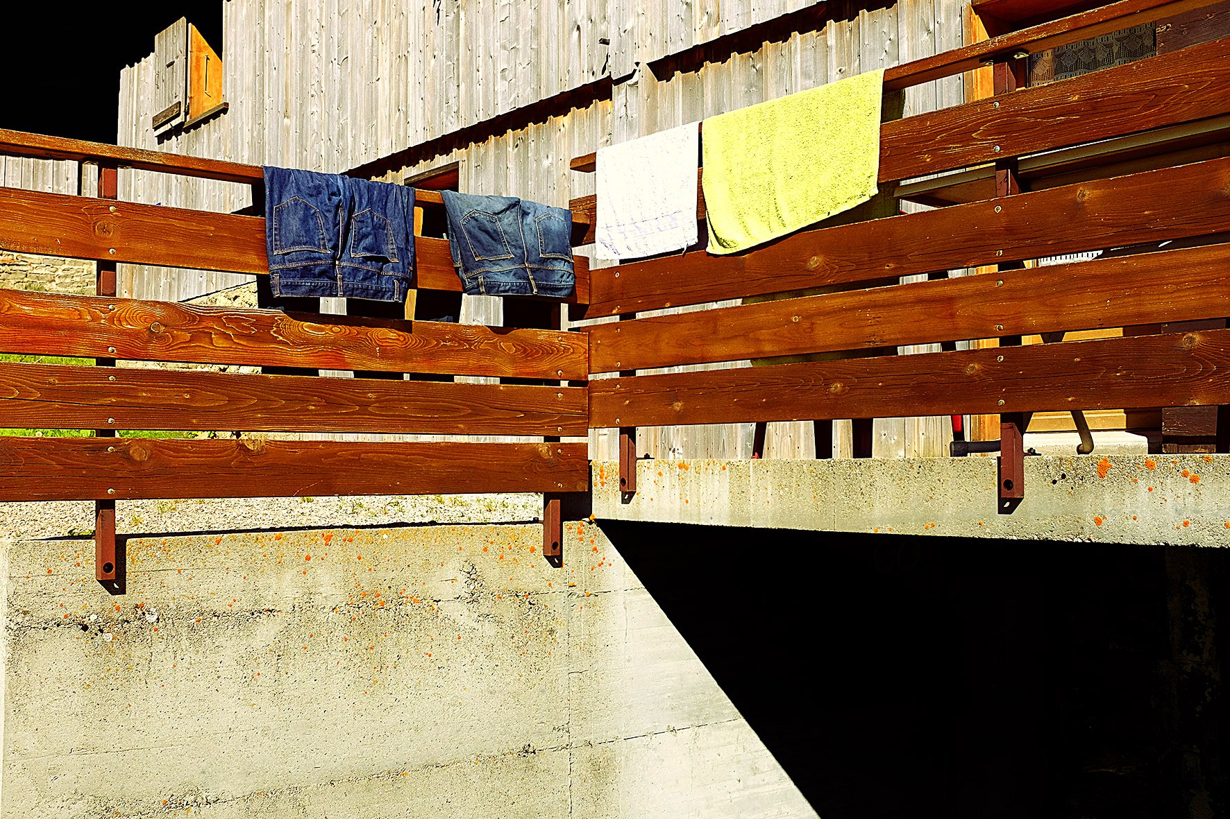 Vêtements suspendus pour sécher, y compris deux paires de jeans, deux serviettes, sur une cloison en bois à l'extérieur.