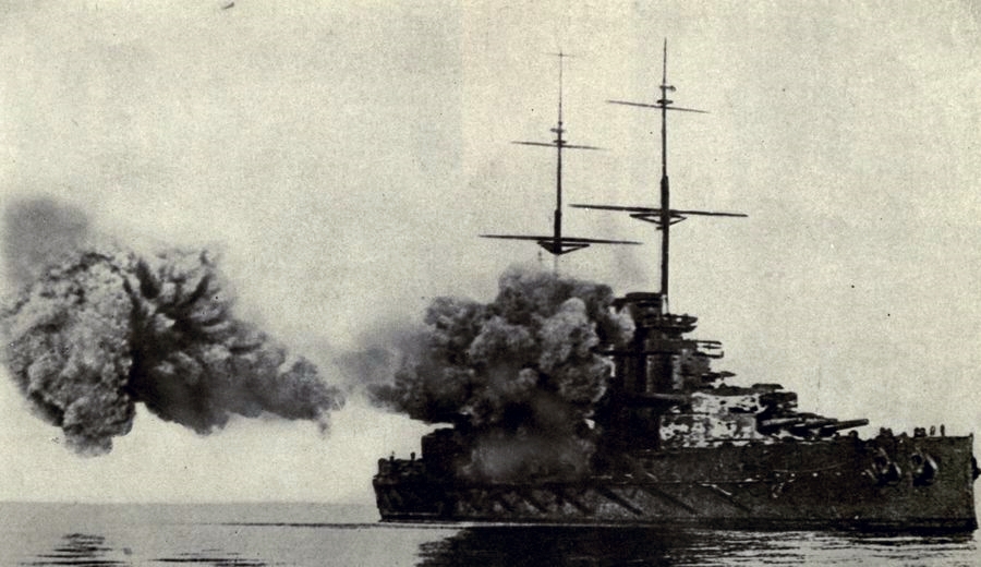 An unidentified British battleship fires its main armament. 