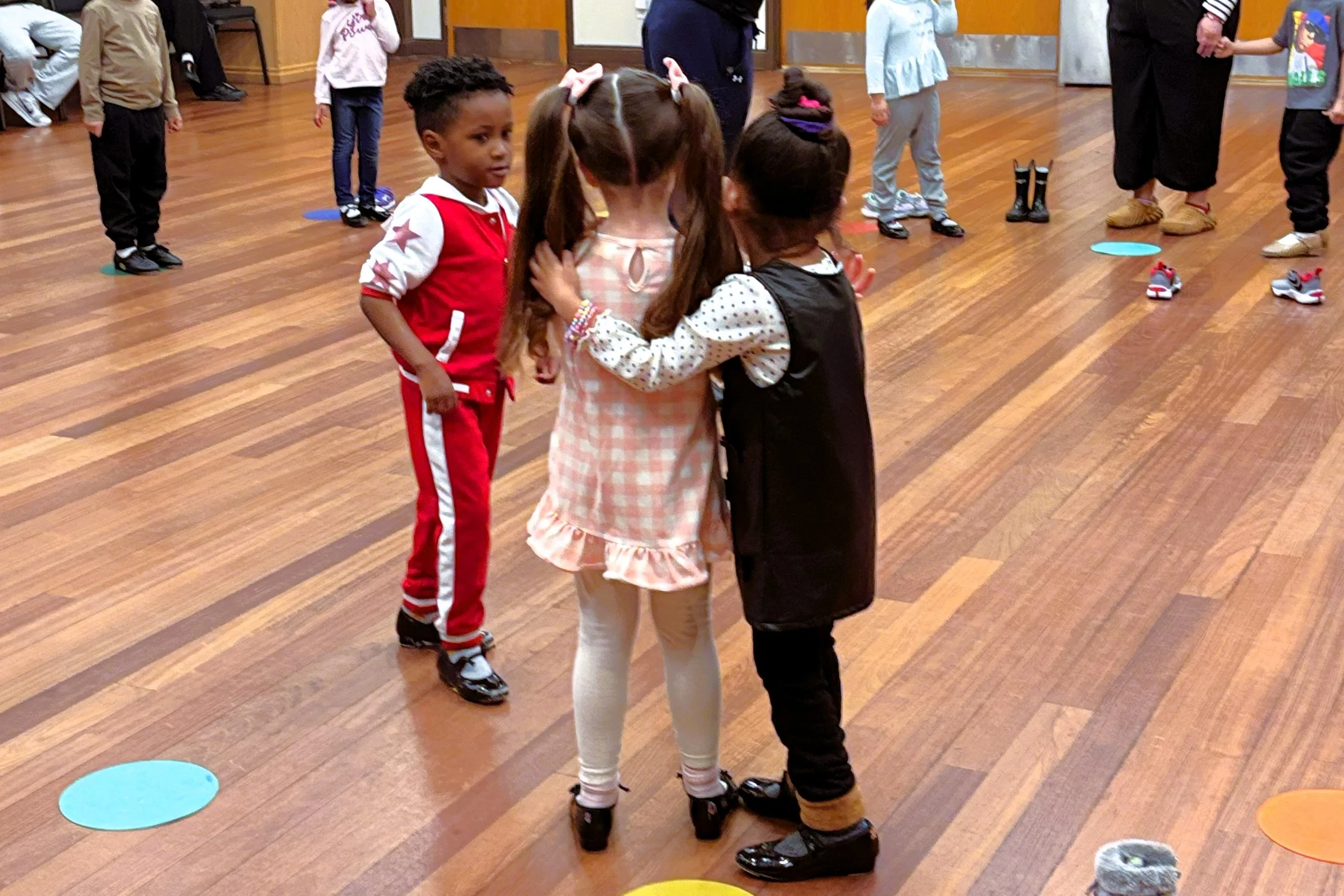 photo of one child talking to two children hugging