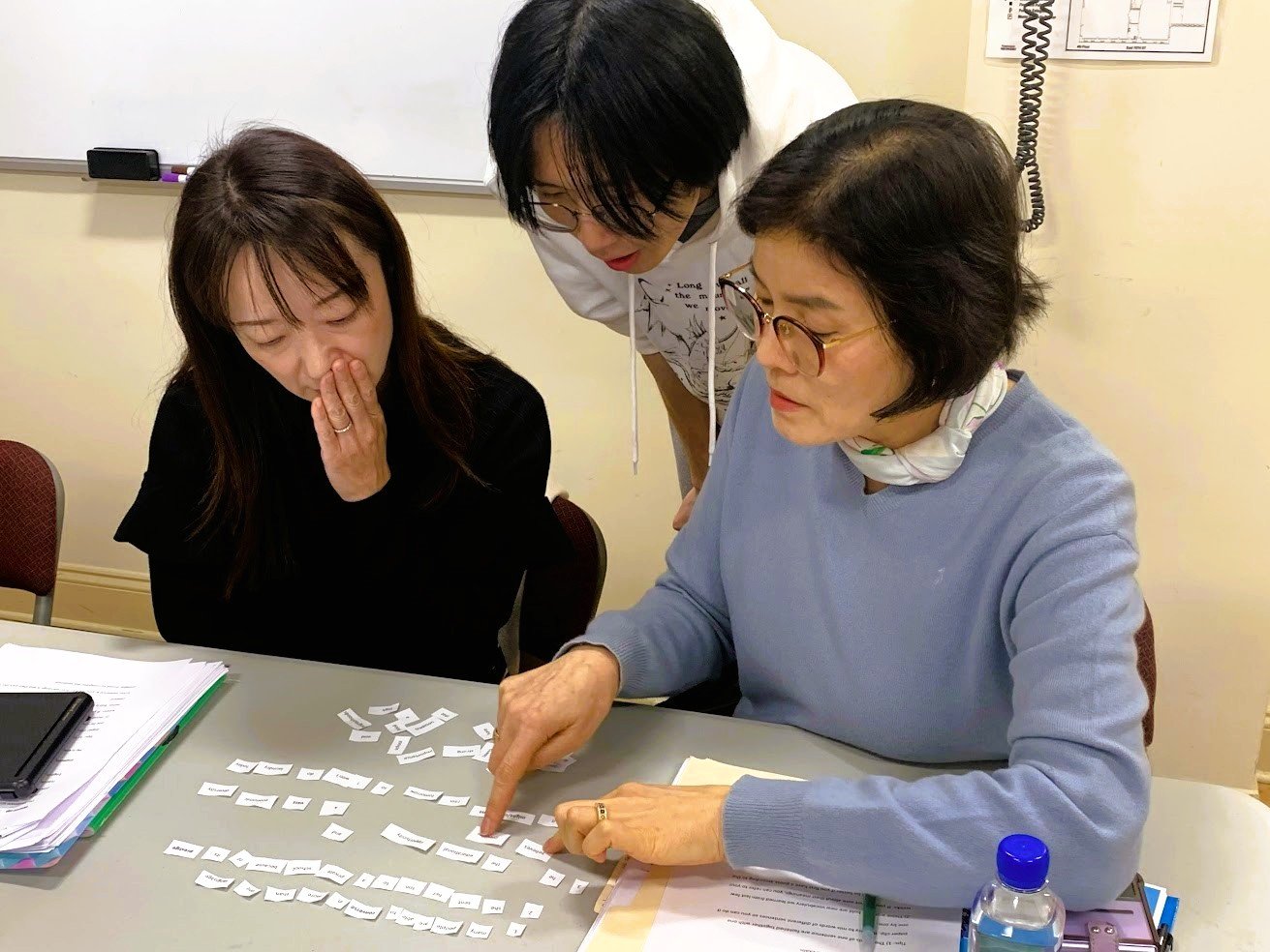 photo of English teacher helping students pronounce words on cut up pieces of paper
