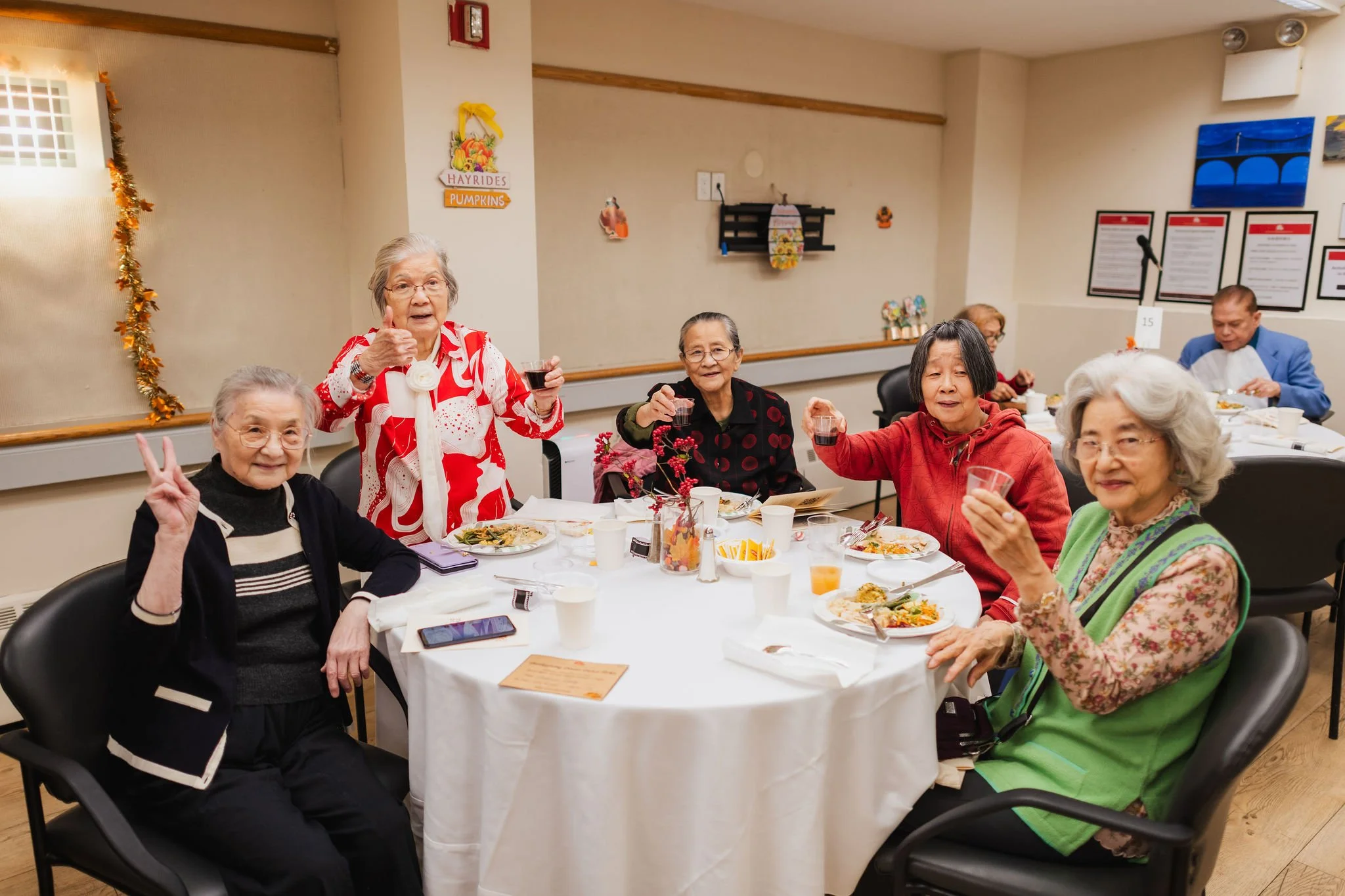 Photo of five women smiling and saying cheers while eating a Thanksgiving meal