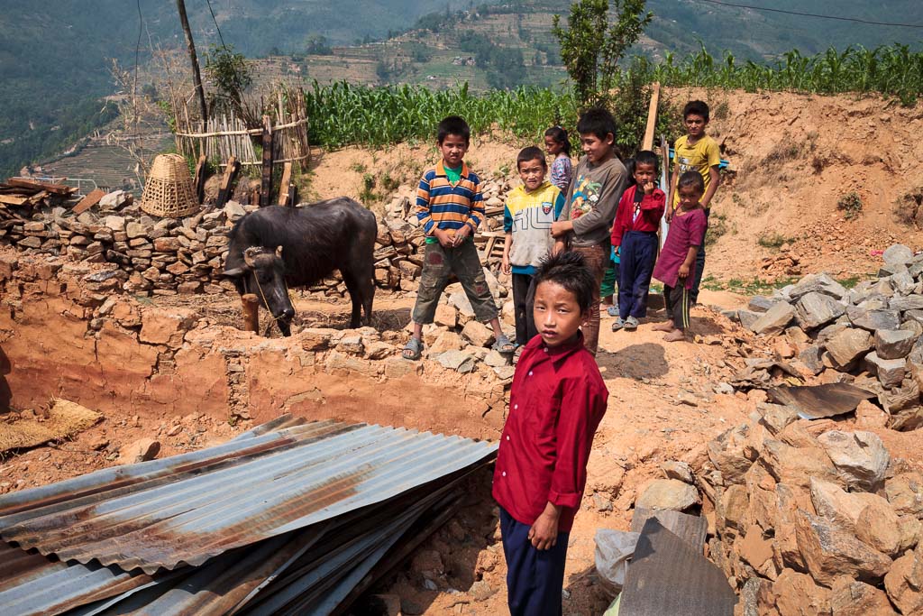  Young boy stands in the rubble of his stone and mud house on the arrival of the Moving Mountain School bag team to distribute bags to the young students many of whom lost family members and their homes on the same day. 