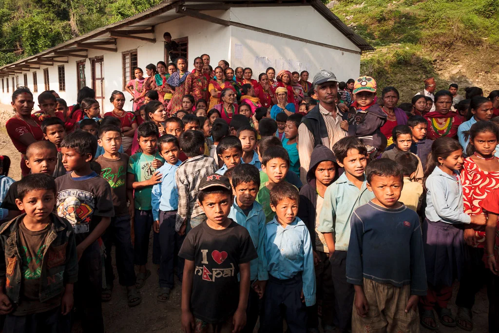 The school children gather outside the hut before being called in to receive their bags.