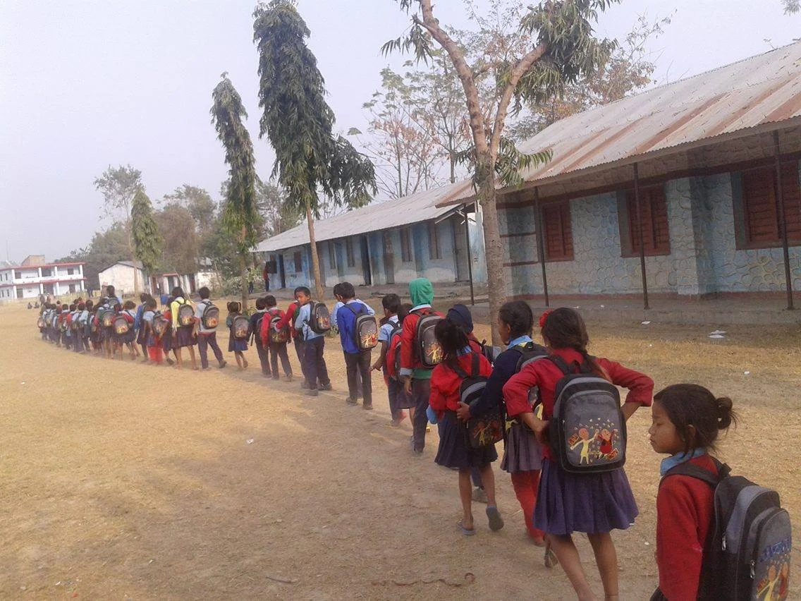 Children in Dudhauli walk in a line after school with Moving Mountain School Bags.