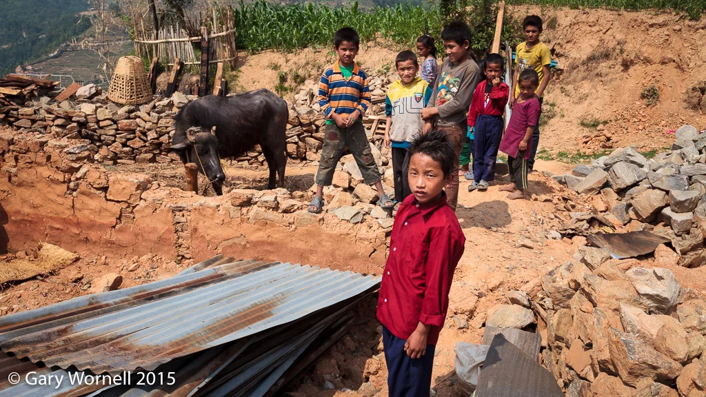 Children of Thakani, Sindupalchok, stand in the rubble of their home, May 19, 2015.
