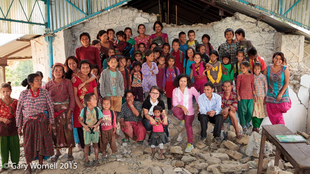 Group photo in the rubble of the collapsed school with the surviving children from the village, teachers, principal, parents and Rewati Gurung - founder of Moving Mountain School Bag and Menka Batachan volunteering.