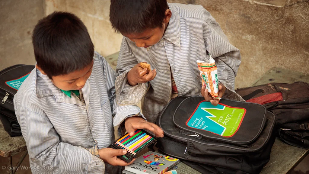 Two boys examine the contents of their new school bags.