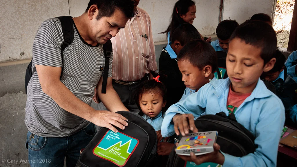 Ganisham Gurung helps a young student go through the contents of her new school bag.