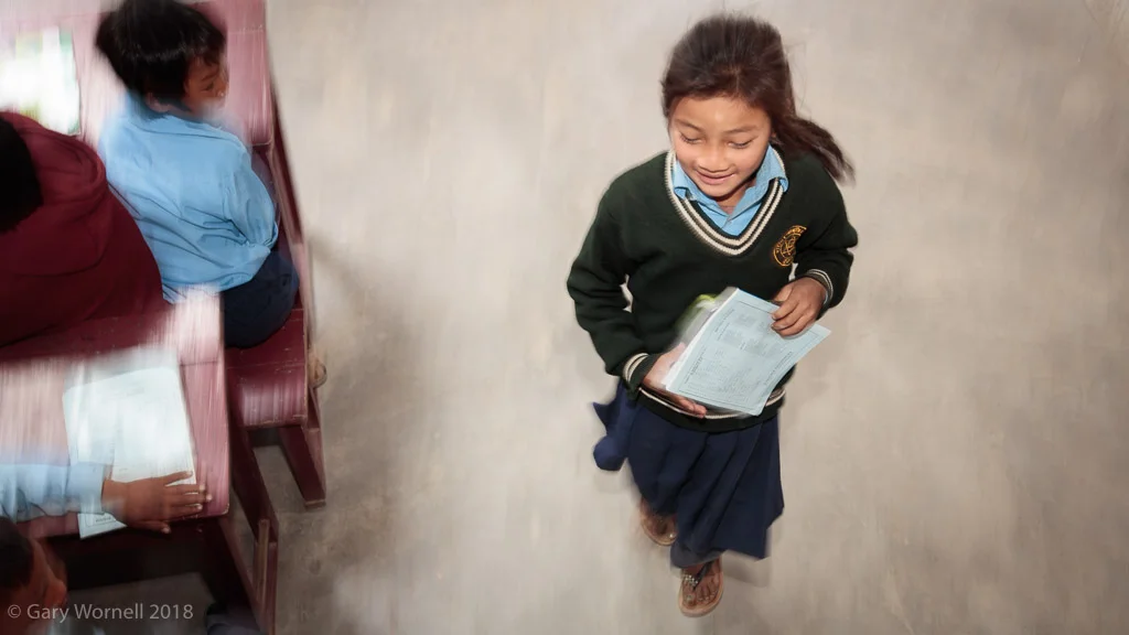 A young girl runs to her desk in preparation for the school bag donation ceremony.