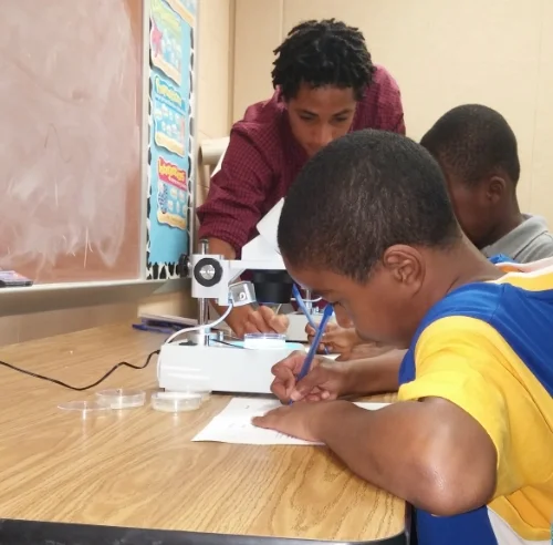 Scientist and volunteer Jordan Drew helps buddings scientists take important notes on worm movement.