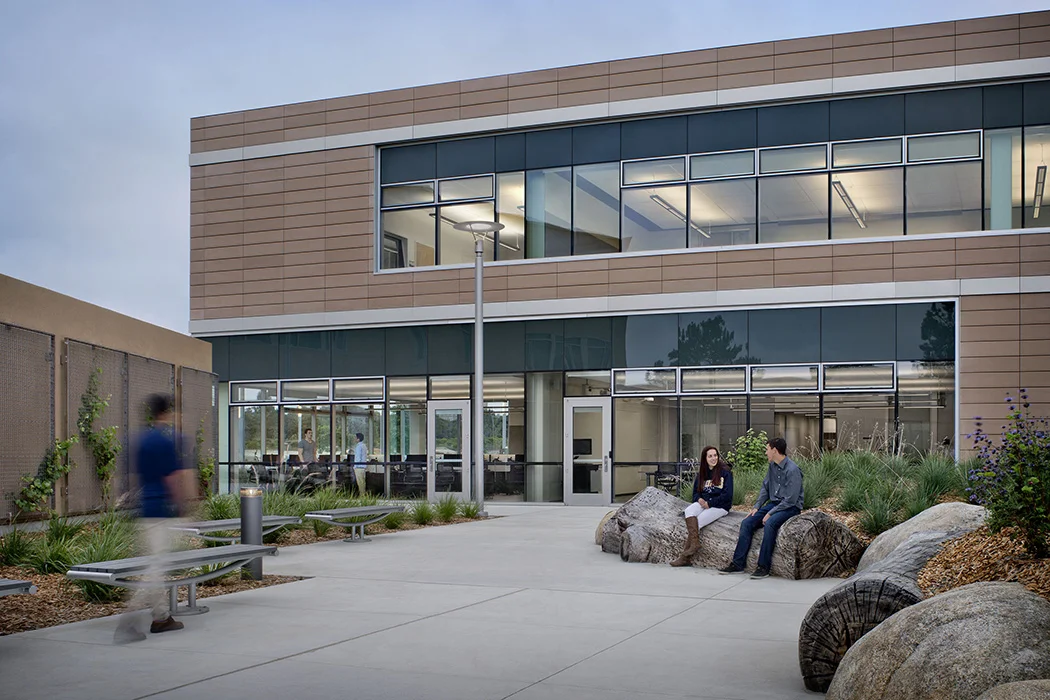 CSUMB Gambord Business and Information Technology Building / Located at the core of CSUMB’s Fort Ord campus, JLJA’s design for the new Joel and Dena Gambord Business & Information Technology Building effectively grounds it in its context, reinforcing connections and linkages to neighboring buildings and academic zones. Like JLJA’s earlier work on the campus’ Chapman Science Academic Center (completed 2003), the design underscores the site’s natural setting and helps to create a sense of place for the university. The landscape draws from local influences of beach, ocean, tide, and wind; these forces form sand dunes, which are the site’s iconic landscape feature. The dunes create habitat for native plants and animals, as well as for systems such as water retention and wind shelter. Certified LEED Gold, JLJA’s design prioritized sustainability by incorporating stormwater drainage, detention basins, and regionally-adapted plant materials. Photo: David Wakely