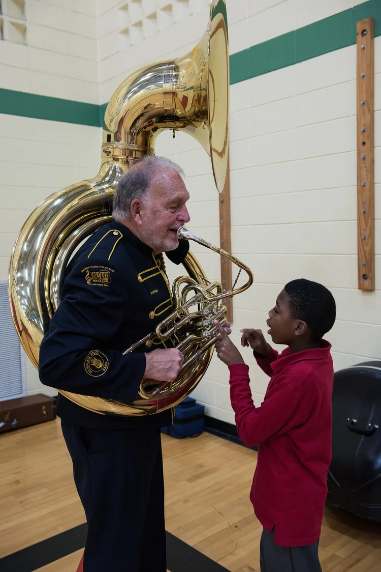Band Member Jim Hopper showing a student his sousaphone.