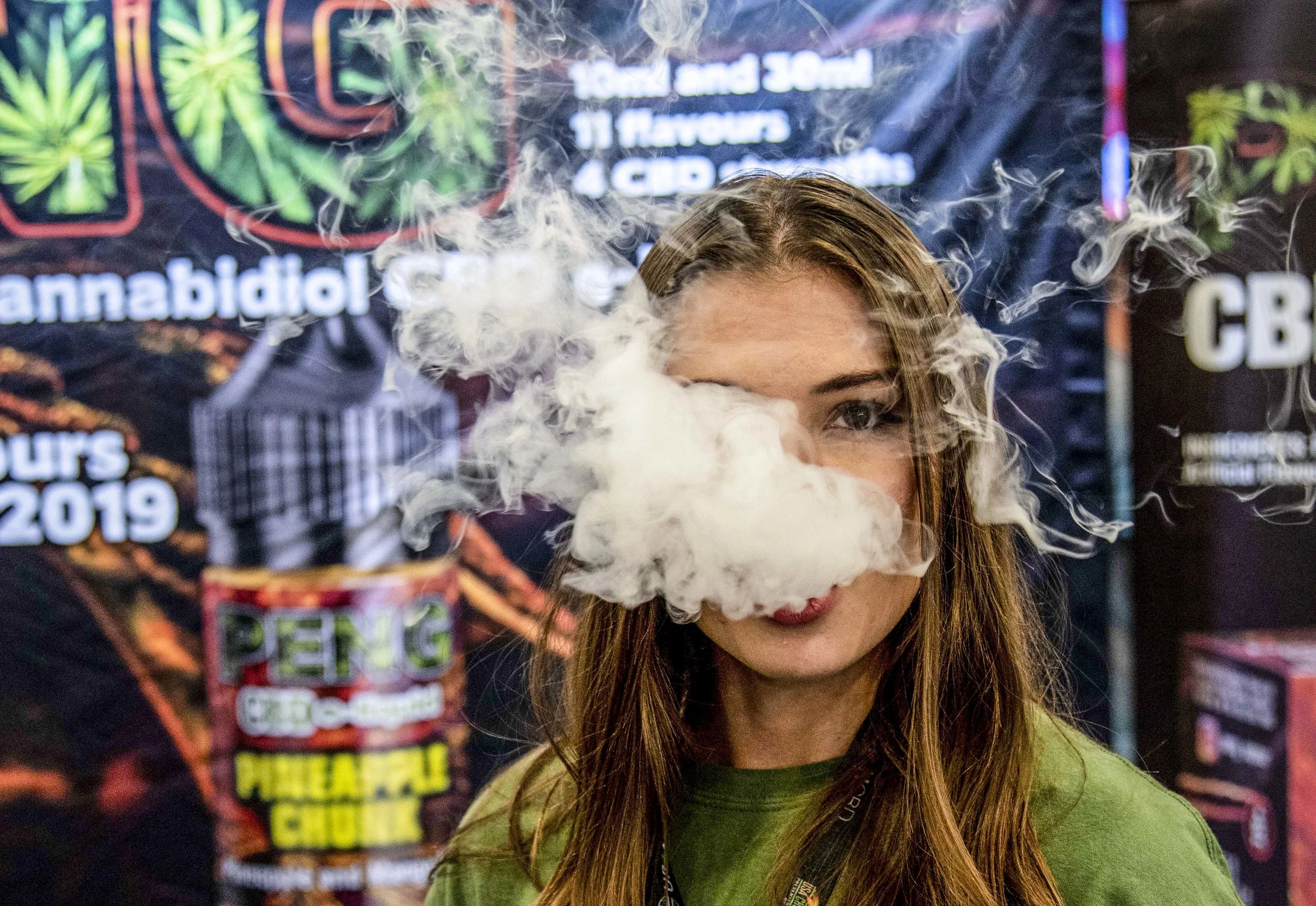 Ruth Carp, 21, the brand ambassador for Peng CBD, blows a cloud of vapor during the USA CBD Expo at the Miami Beach Convention Center on August 2, 2019.