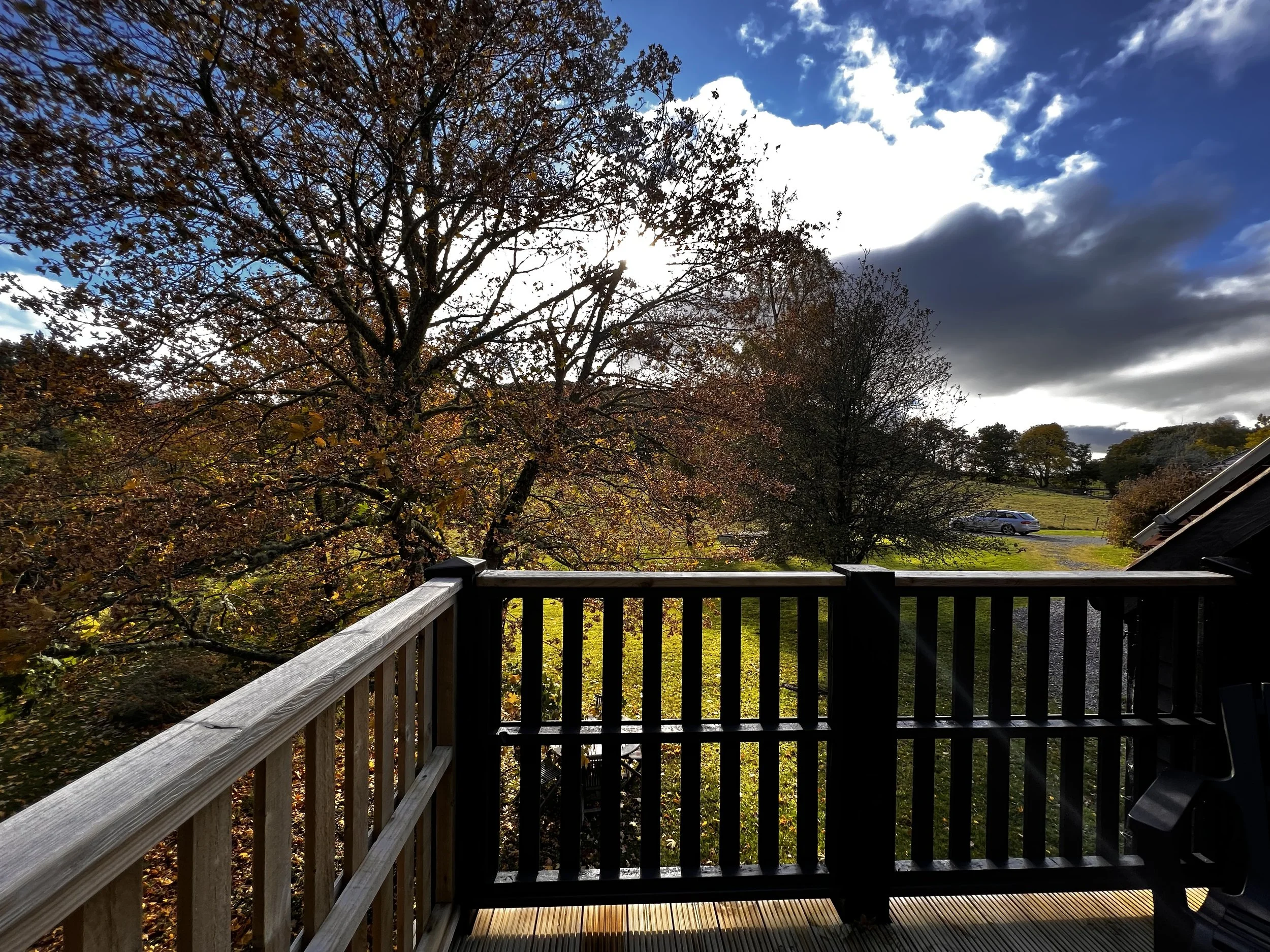 Autumn view from The Hayloft deck across trees and open countryside in the Cairngorms.