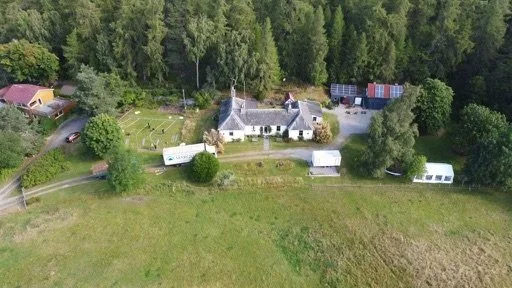 Aerial view of The Hayloft and neighbouring buildings surrounded by countryside and woodland at Rothiemurchus.