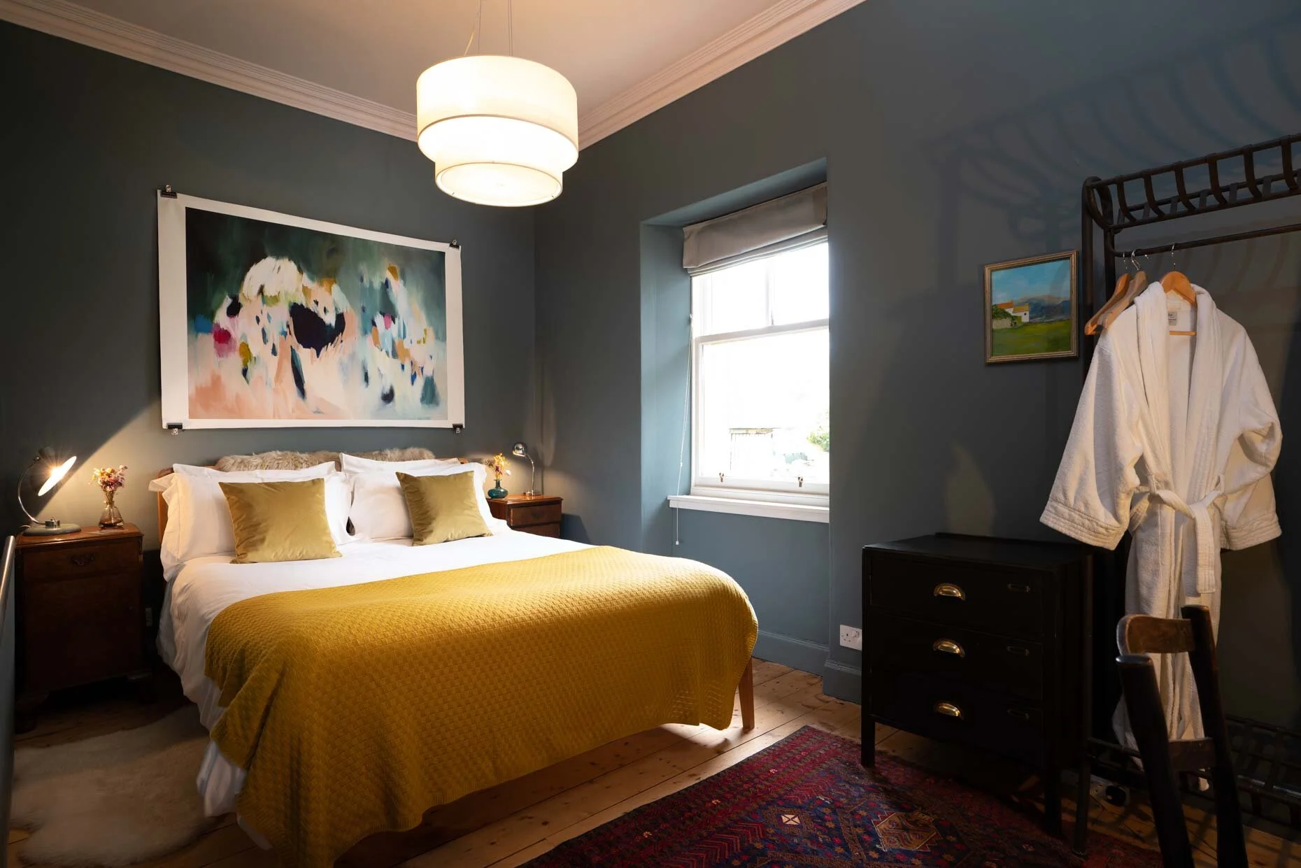 Double bedroom with deep blue walls, mustard bedding and views towards Insh Marshes.