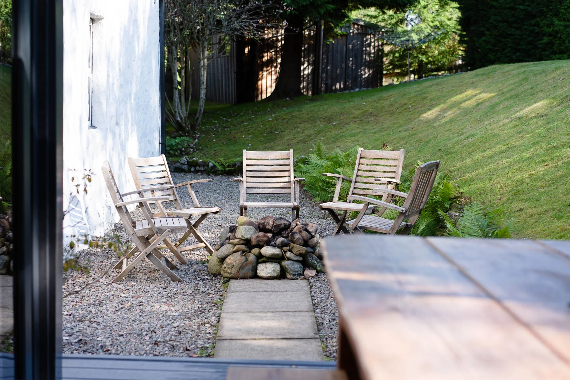 Private garden with outdoor chairs gathered around a stone fire pit.