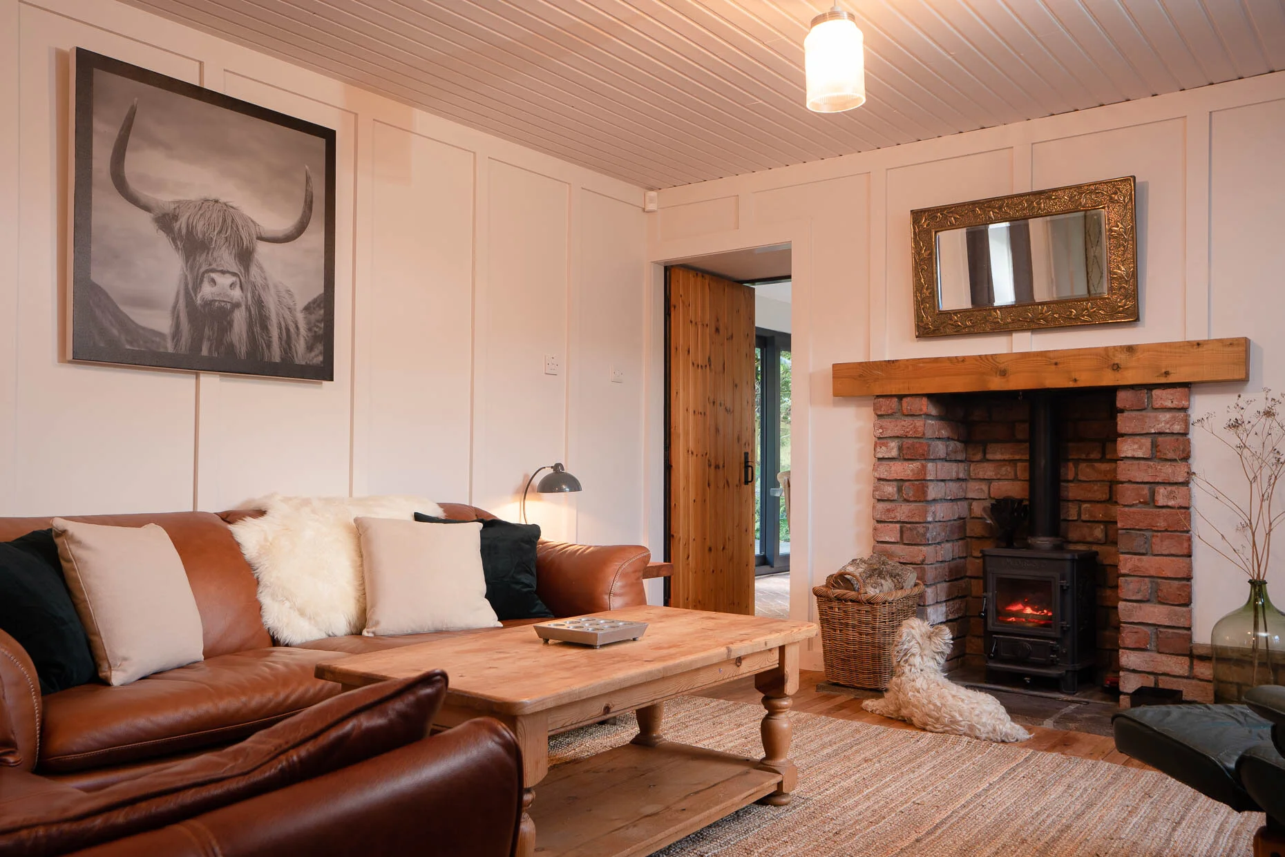 Cosy sitting room with wood-burning stove, leather sofa and rustic wooden coffee table.