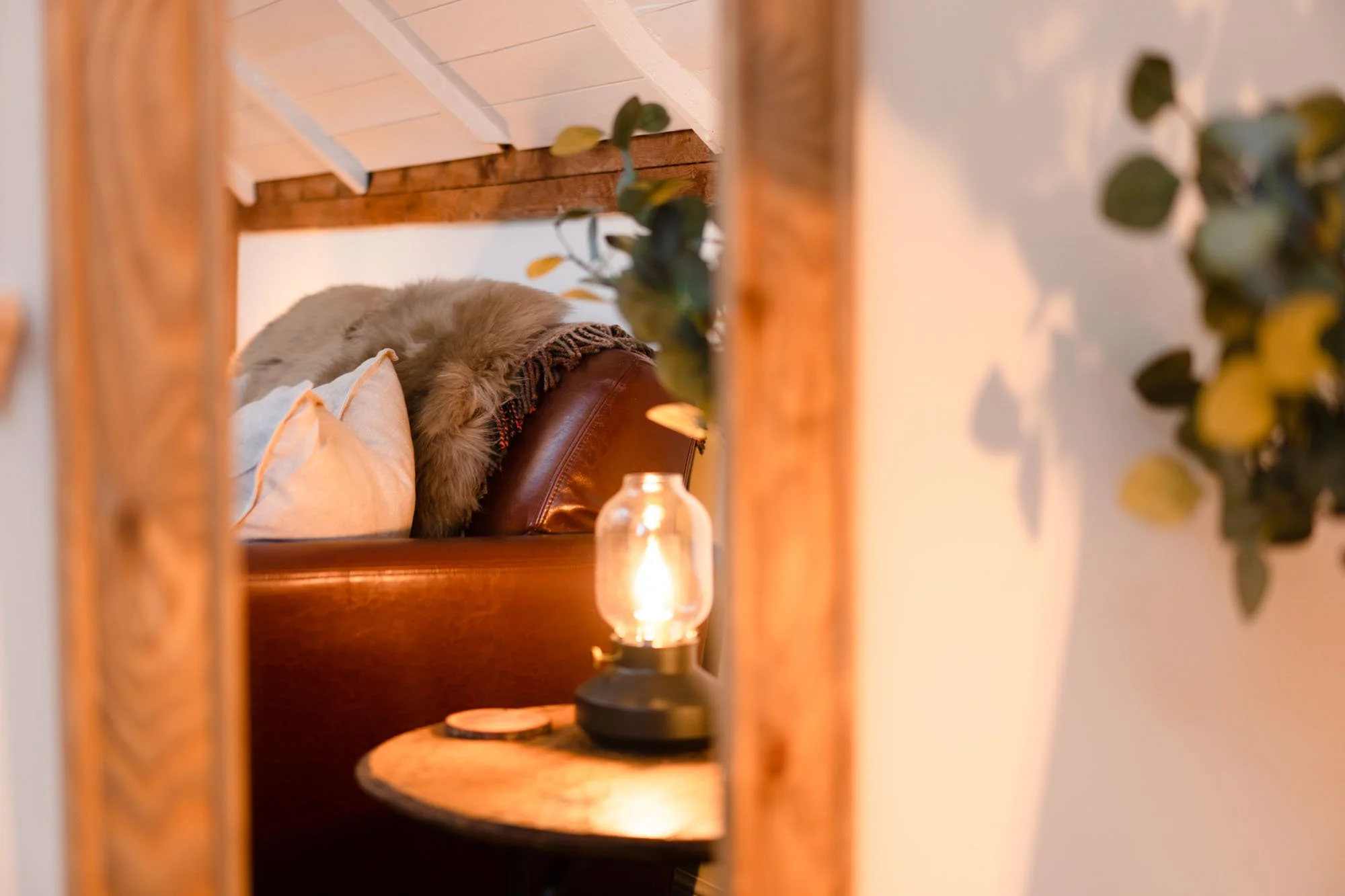 Warm bedside detail in The Hayloft bedroom, with wooden furniture, lamp and soft natural textures.