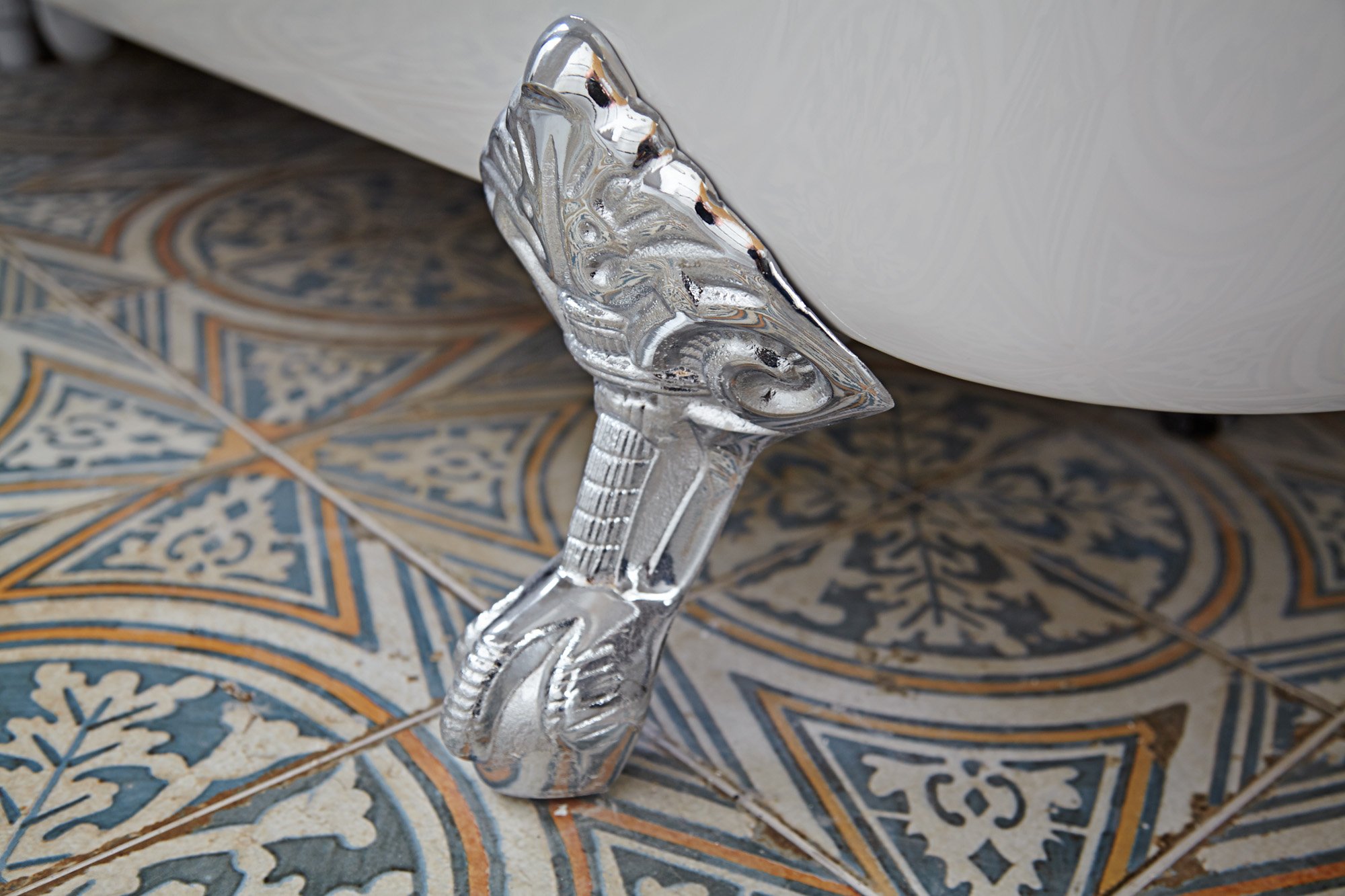 Close-up of a decorative glass seahorse table leg next to a white cabinet on patterned tile flooring.