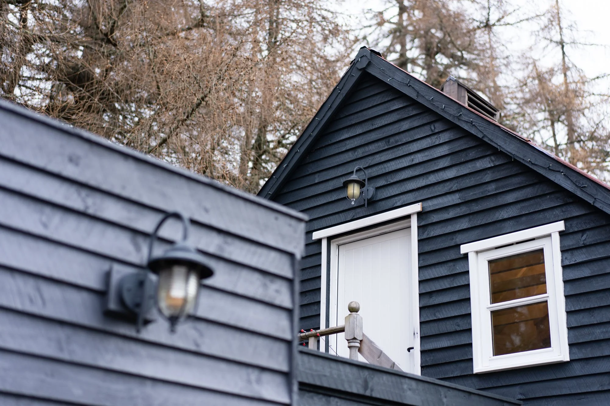 Black timber exterior and entrance to The Hayloft in its woodland setting at Rothiemurchus.