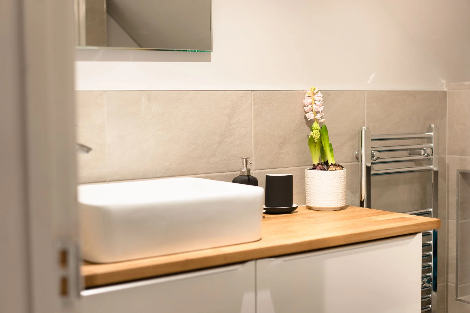 Bathroom basin and wooden countertop at The Hayloft, with simple flowers and contemporary fittings.
