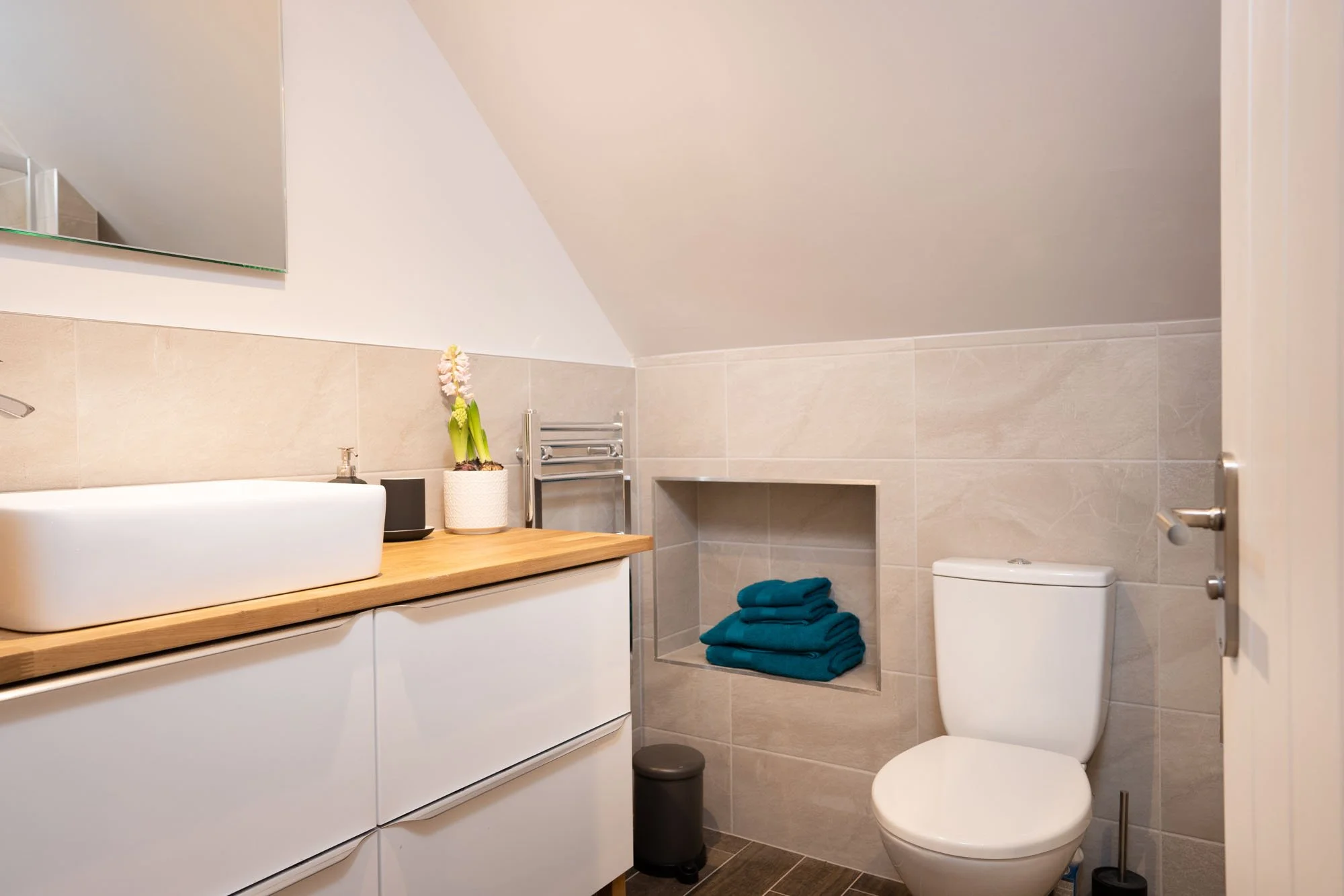 Modern shower room at The Hayloft with walk-in shower, white suite and neatly folded towels.