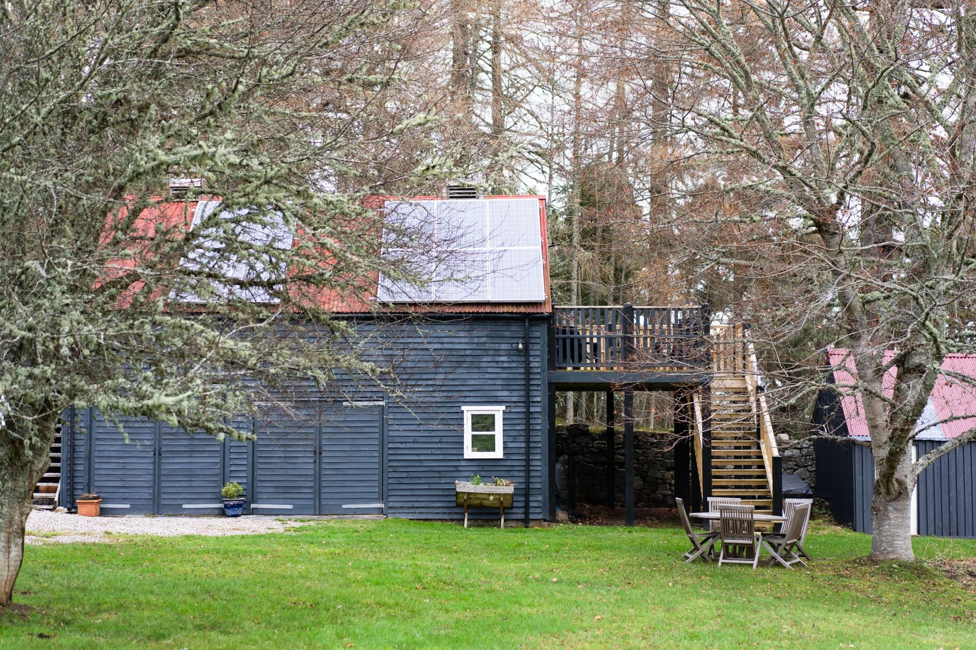Exterior of The Hayloft, a black timber self-catering cottage surrounded by woodland at Rothiemurchus in the Cairngorms.