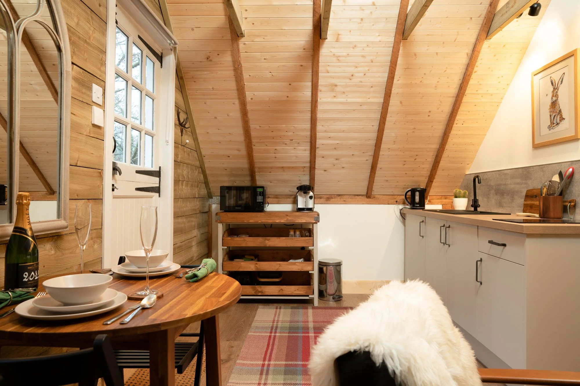 Compact kitchen and dining area at The Hayloft, with wooden worktops and timber vaulted ceiling.
