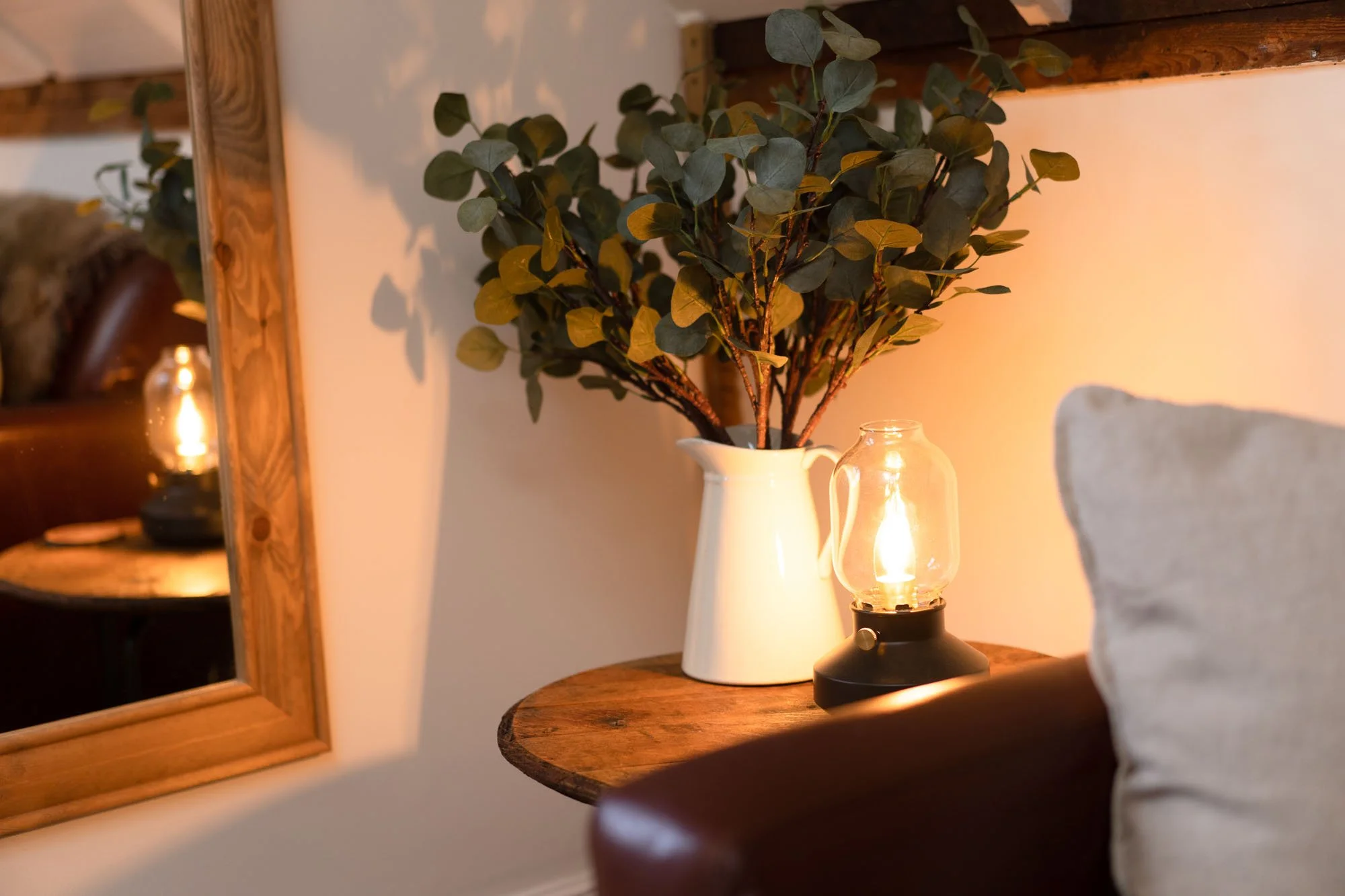 Decorative foliage, ceramic jug and warm lamp creating a cosy atmosphere inside The Hayloft.