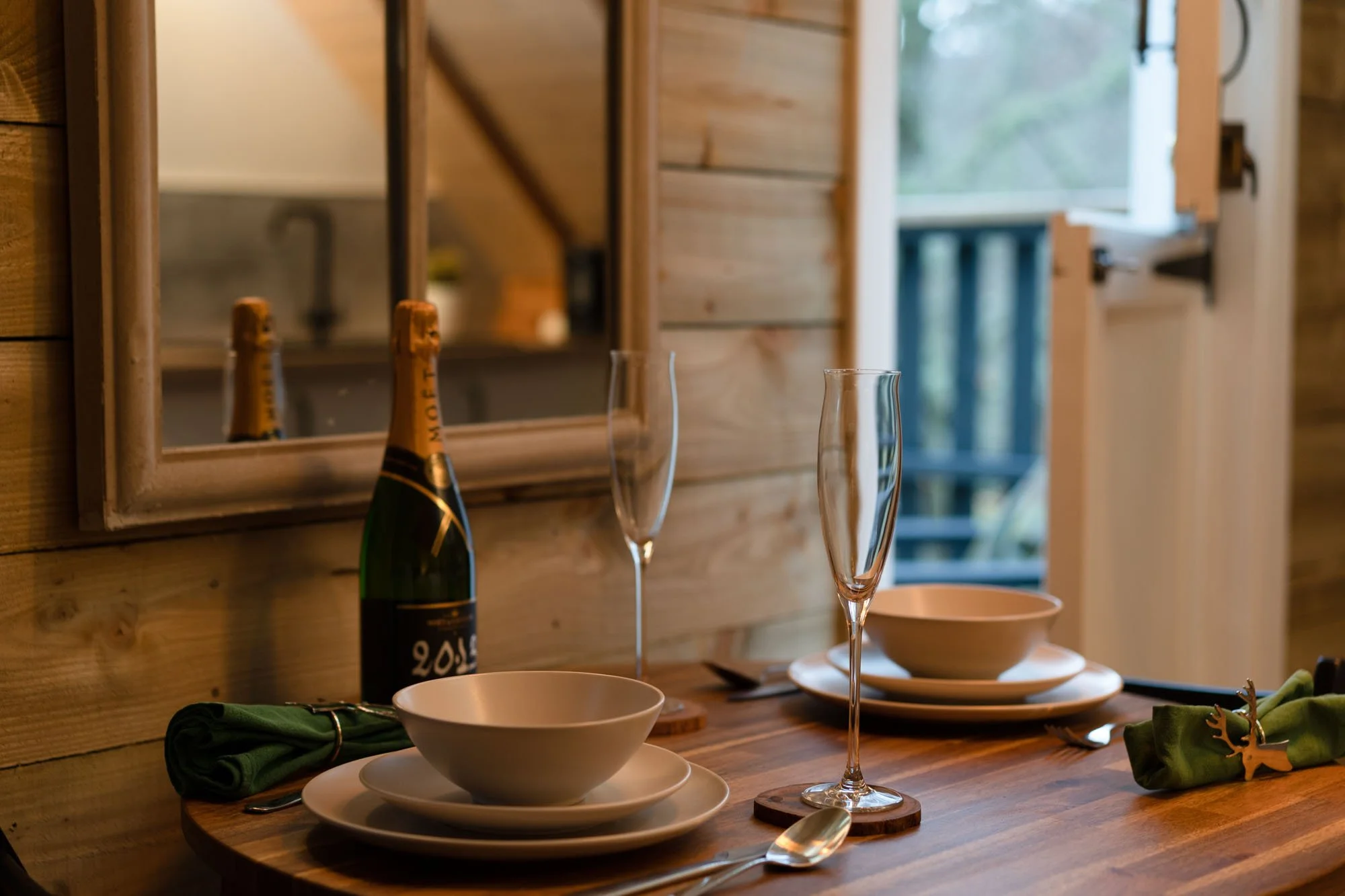 Dining table set for two at The Hayloft, with champagne and doors opening onto the private deck.
