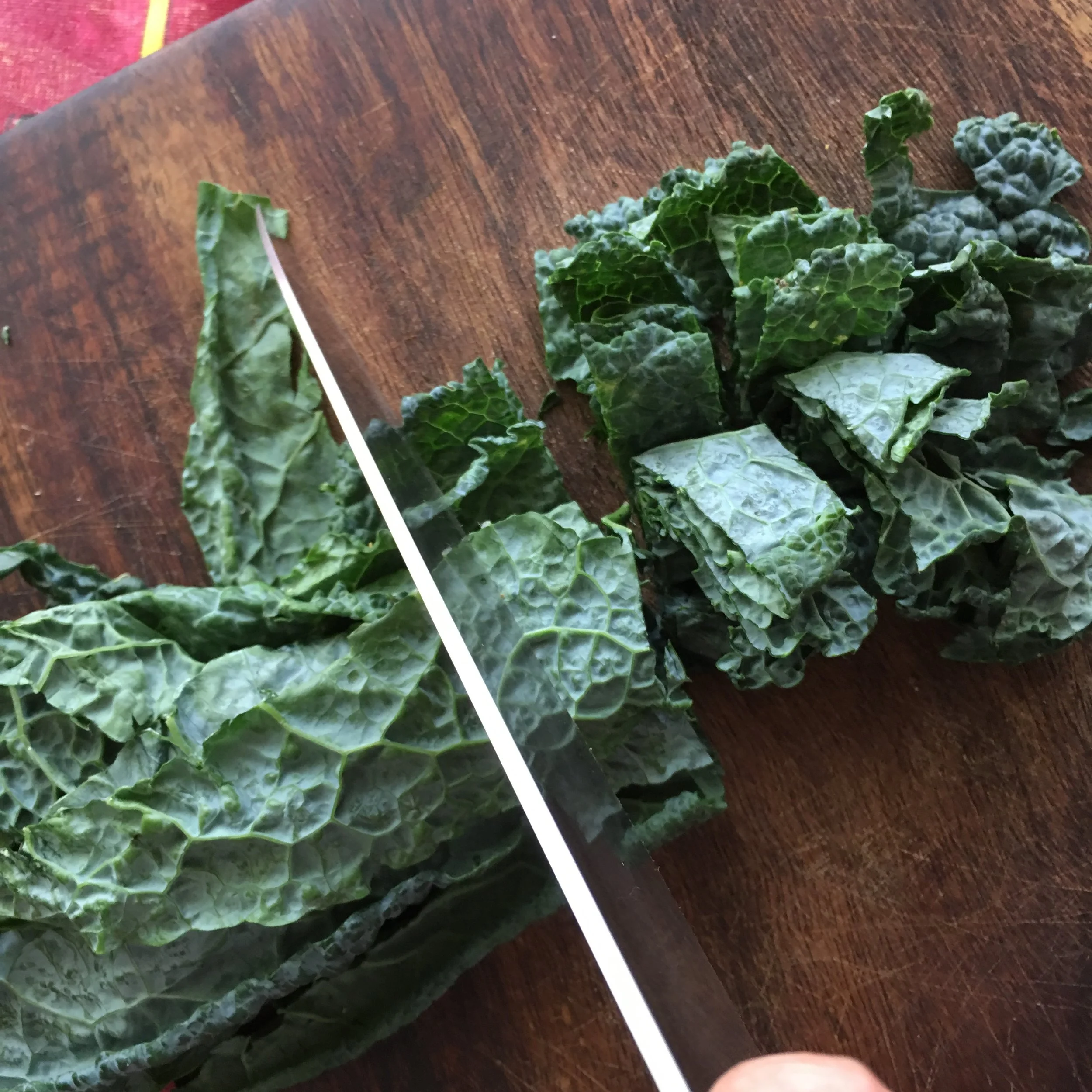    chopping stacked and rolled kale leaves in a chiffonade style cutting technique...   