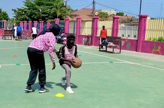 Coach Bintou teaching a student to dribble