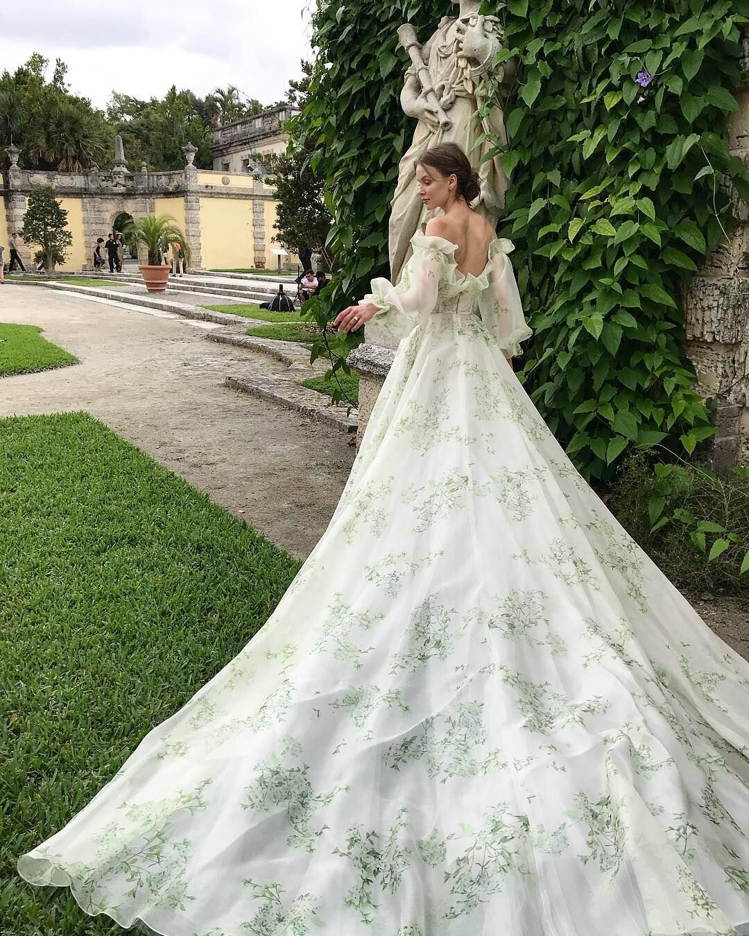 Whimsical off-the-shoulder ball gown wedding dress with green floral detail by Monique Lhuillier.