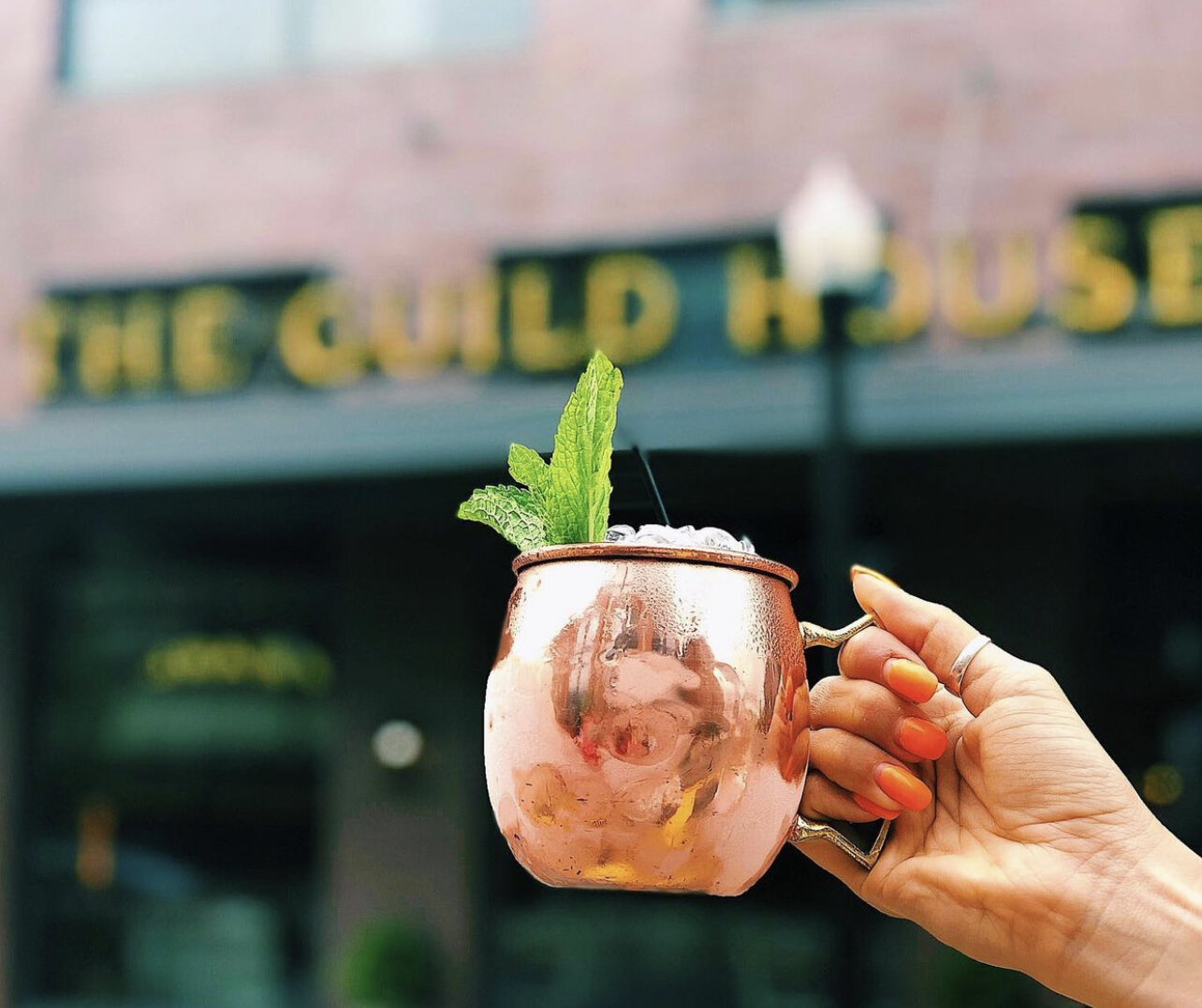 A cocktail being held in front of The Guild House; a restaurant located in the Short North.