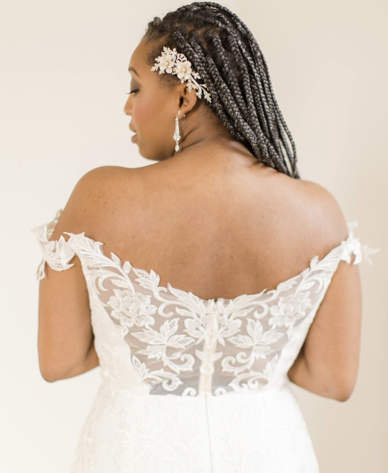 Bride wearing an off-the-shoulder wedding dress with a Paris by Debra Moreland hair accessory.