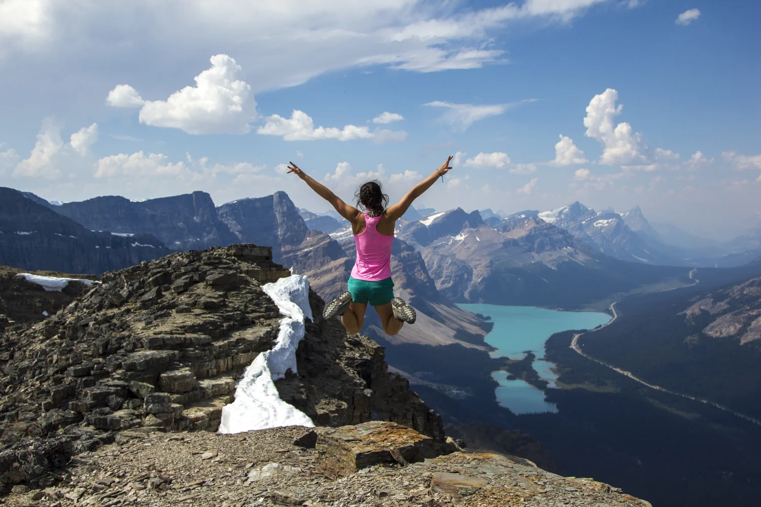 A hiker jumps on top of Bow Peak.