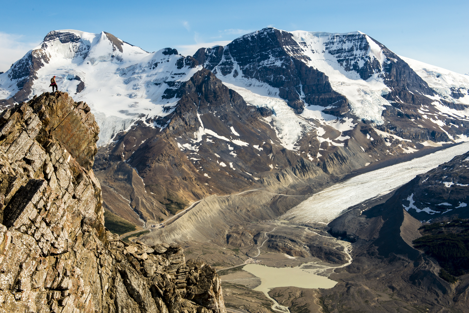 A hiker enjoys grandeur views of the Columbian Icefields and glaciers surrounding Mt Athabasca.
