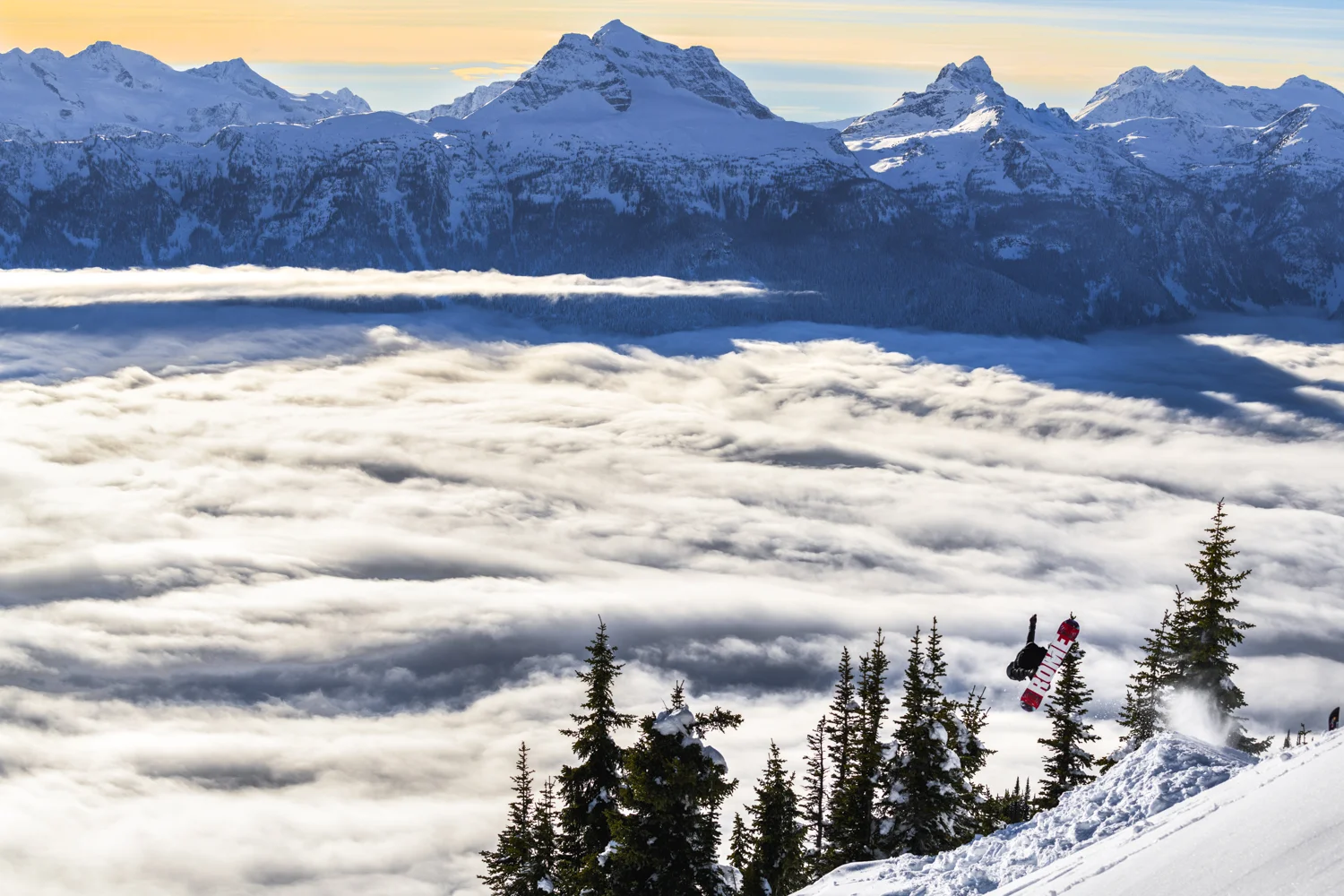 A snowboarder enjoys beautiful inversions in the back country of Revelstoke mountain resort.