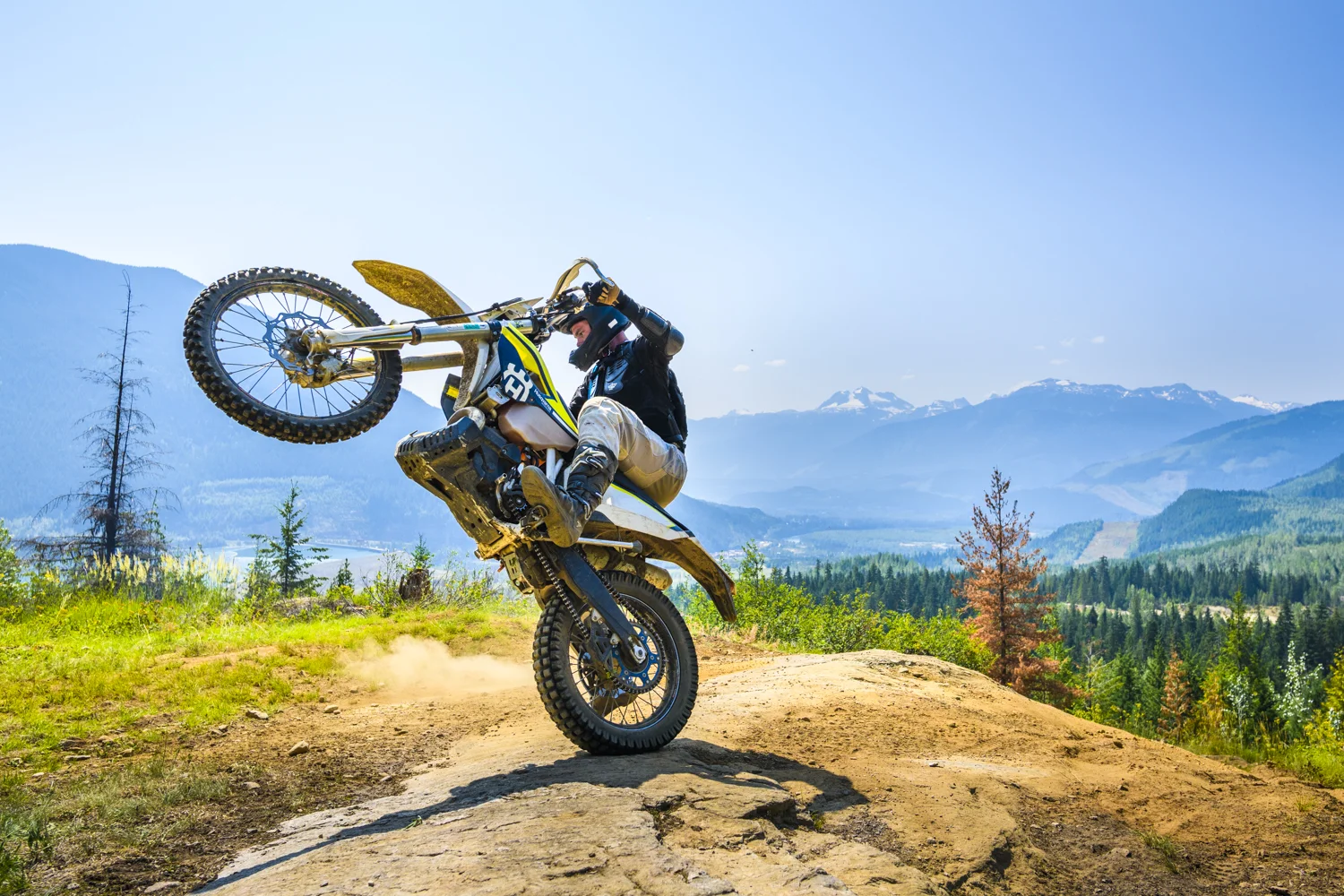 A dirt biker throws a wheelie on local Revelstoke trails in British Columbia.