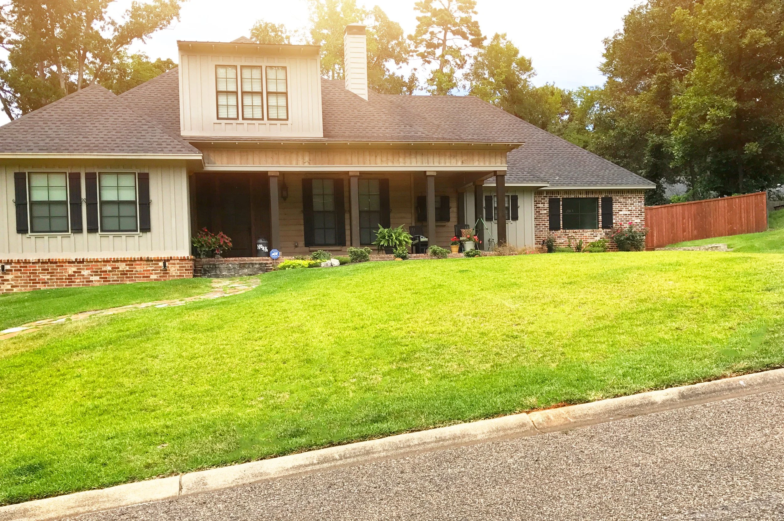 Front view of a house with a porch, brick and siding exterior, and a well-maintained lawn.